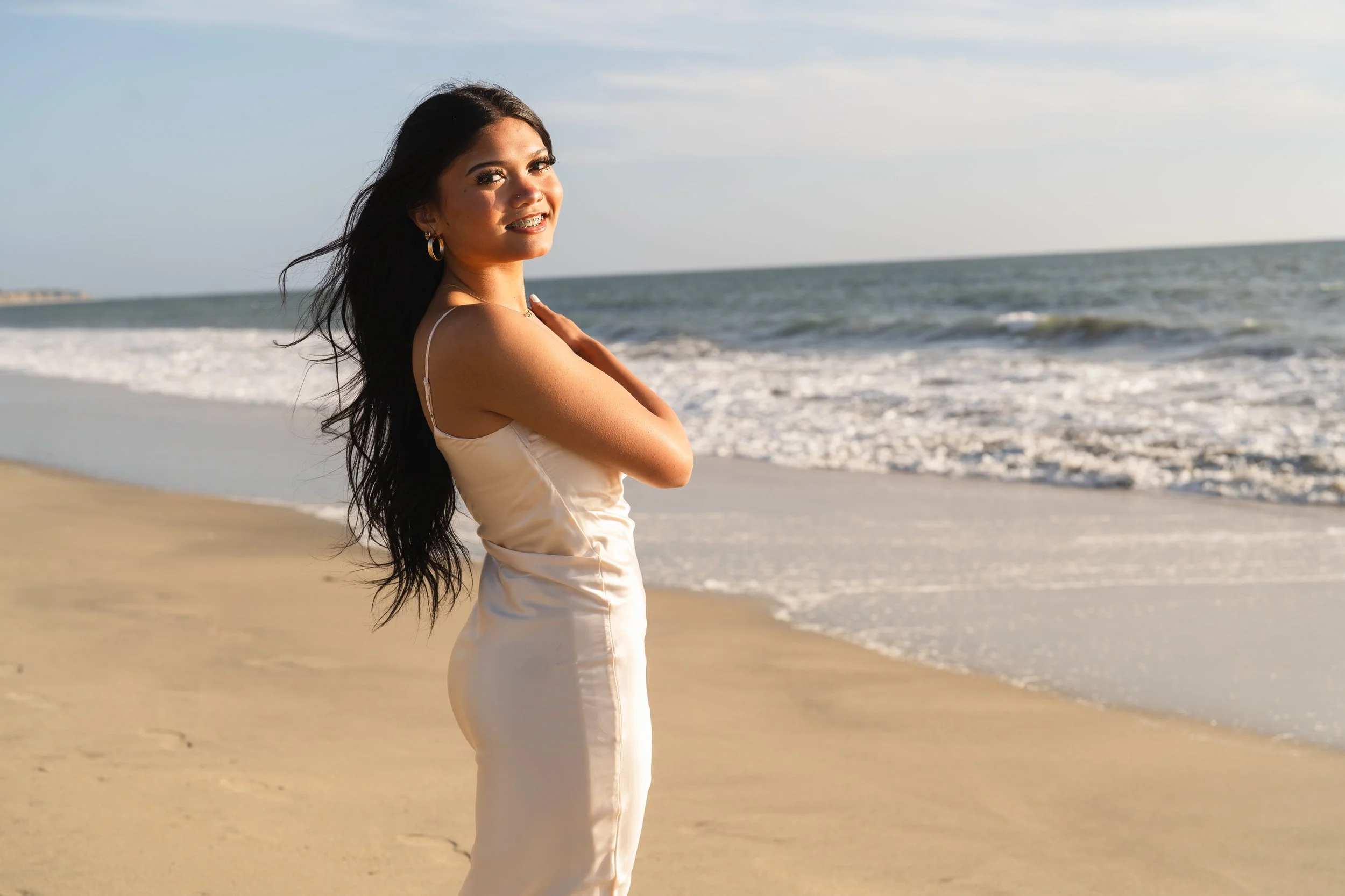 Class of 2027 senior smiling beside the ocean during her senior portrait session in Half Moon Bay, California