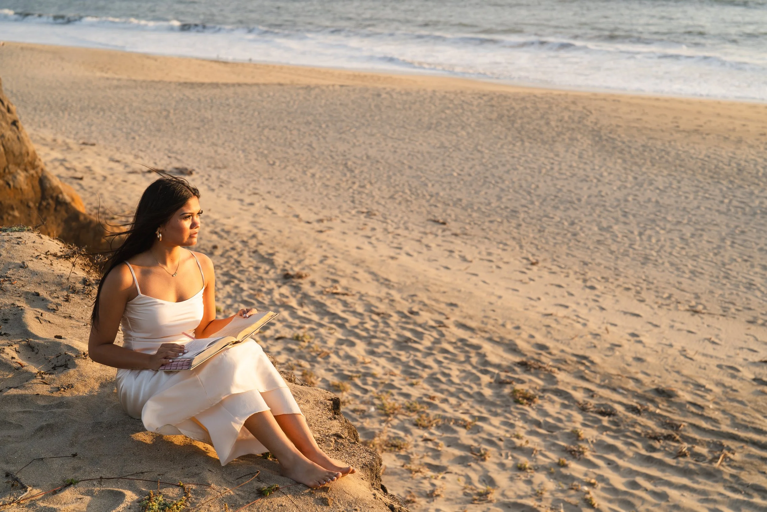 High school senior sitting on the dunes reading her Bible in golden light at Half Moon Bay