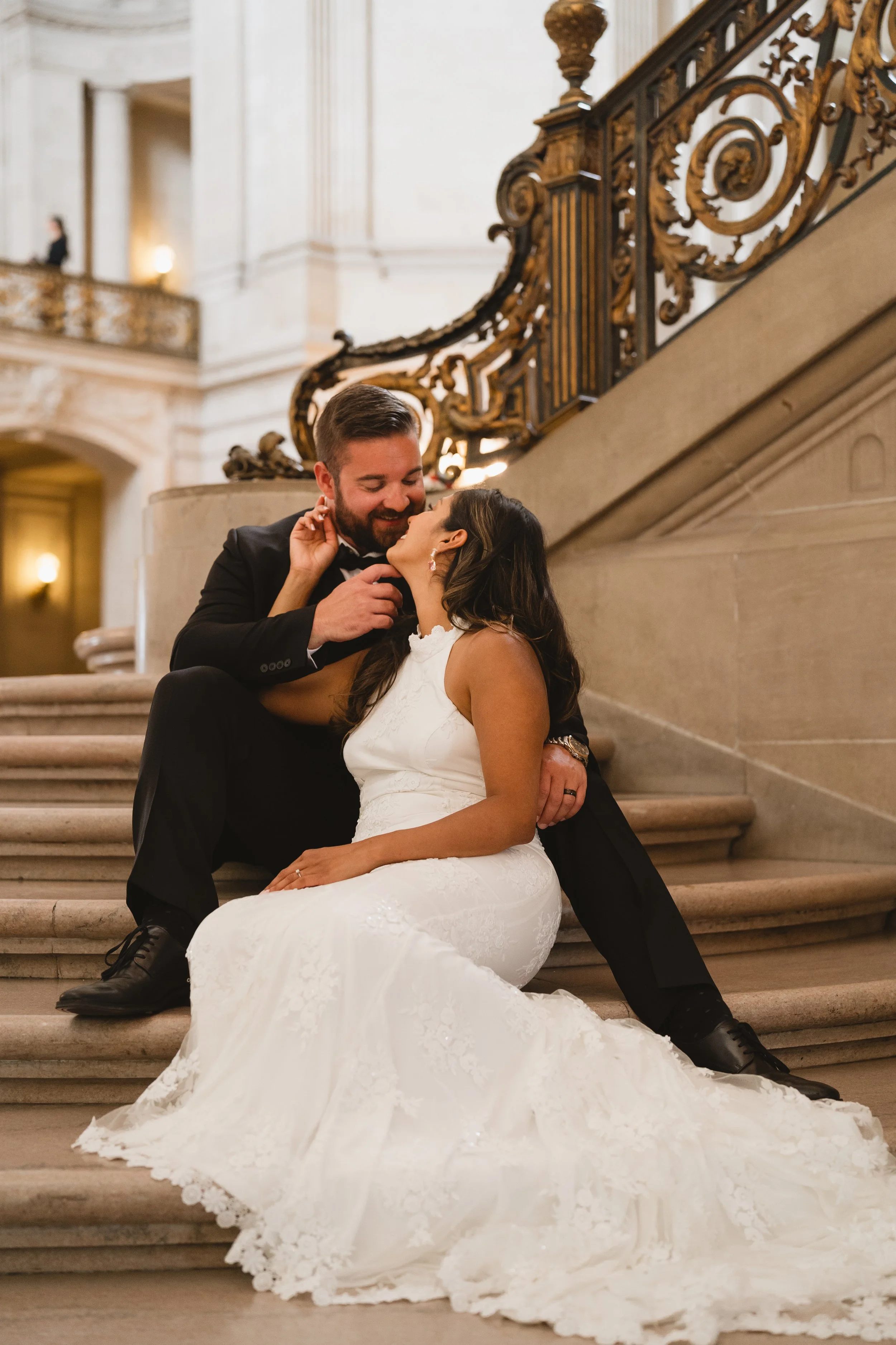 Couple seated together on the marble staircase steps, laughing in a close embrace.