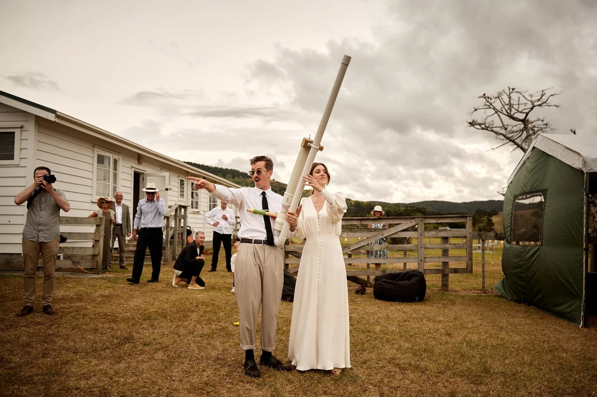 Playful countryside wedding photo of a bride and groom participating in outdoor games, captured in a candid, documentary photography style