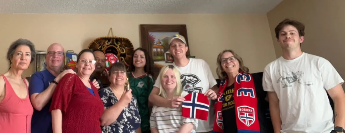 A group of 10 diverse people in a family room with some Norway colors and flag, and some Mexico colors and jersey