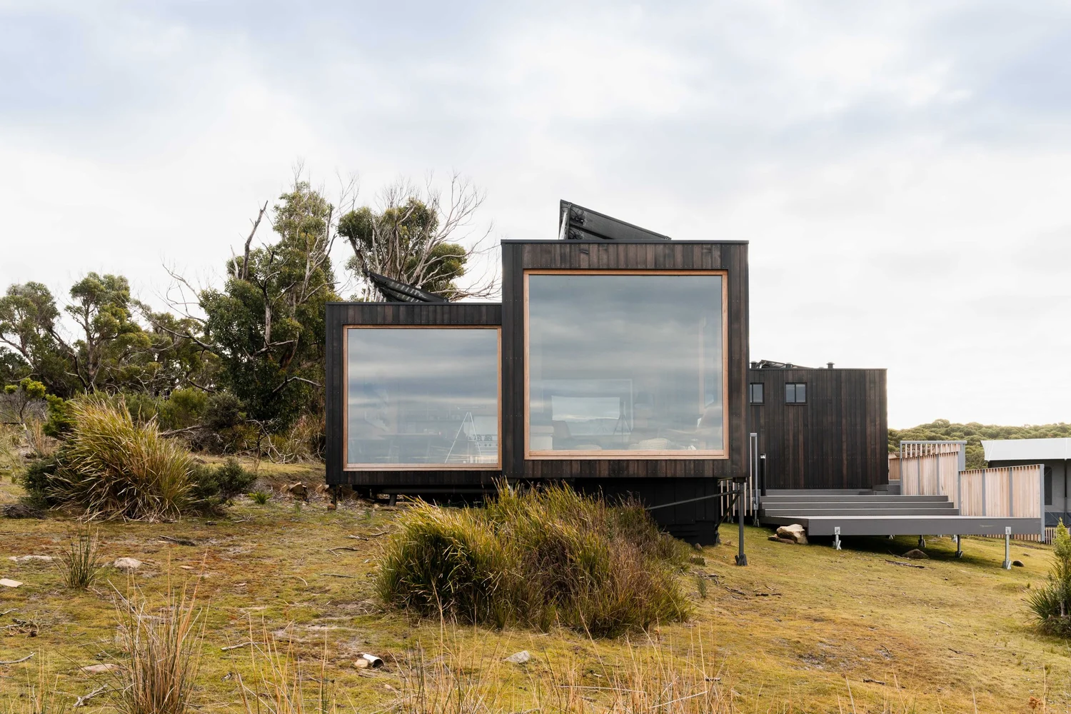Floor-to-ceiling glazing framing sea-cliff and water views inside the off-grid Tasman Peninsula pavilion