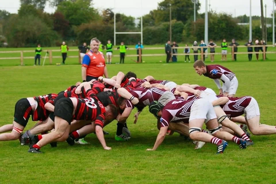 Clane RFC forwards in a scrum against a team in maroon
