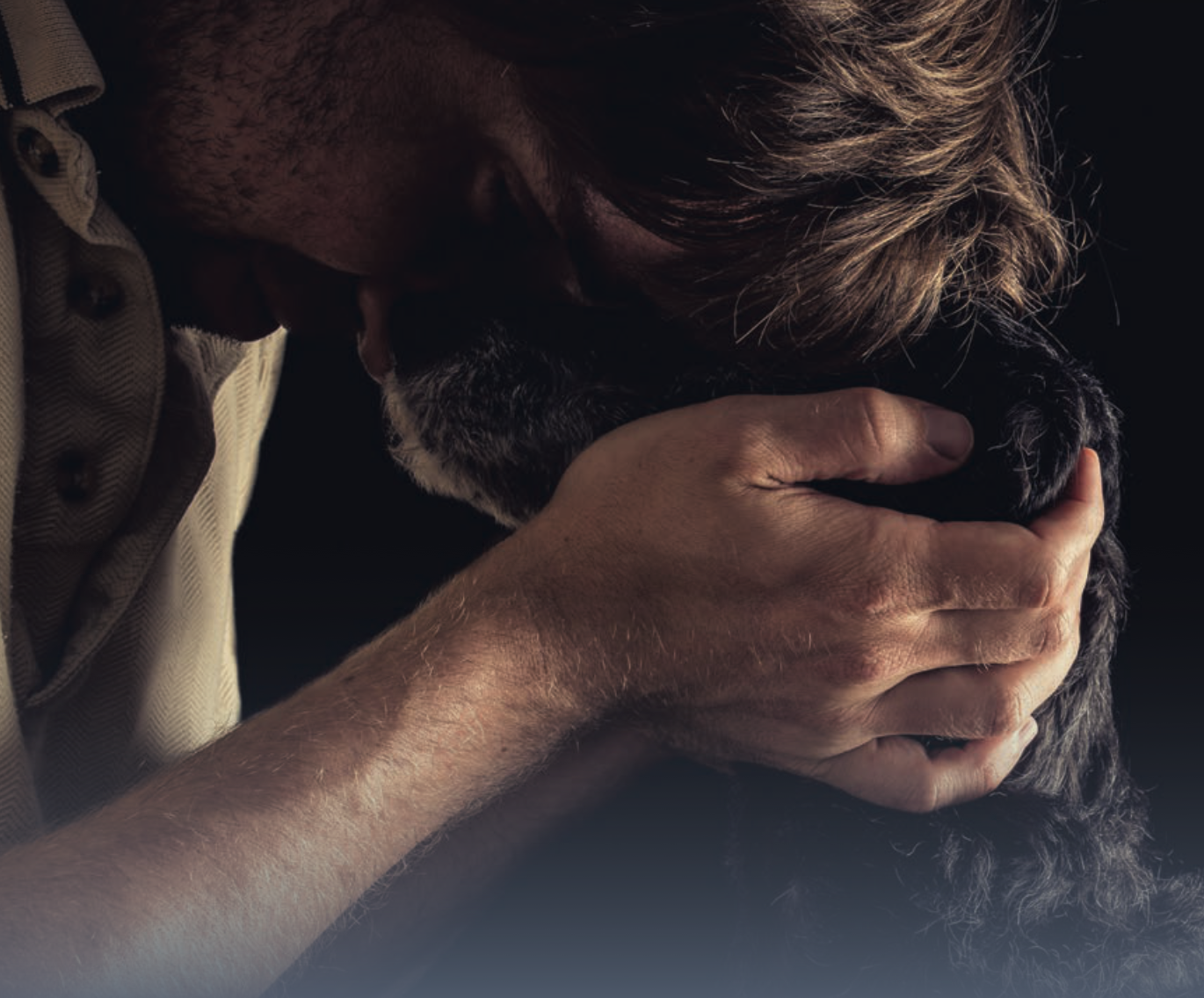 man holding dog's face with head pressed up against dog's representing the strong human-animal bond