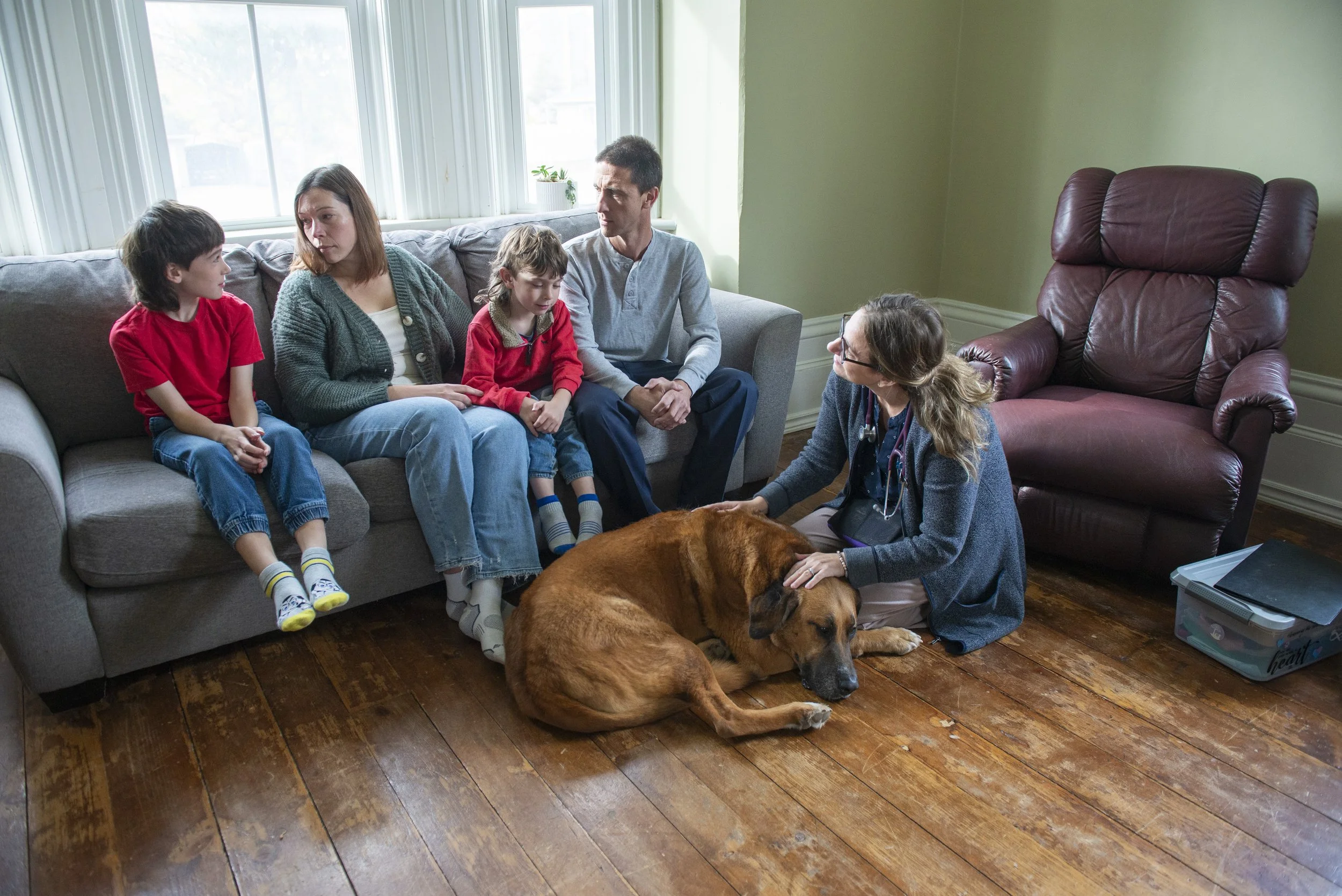 Family sitting on couch with parents and 2 children, large breed dog sitting on floor with Dr. Erica