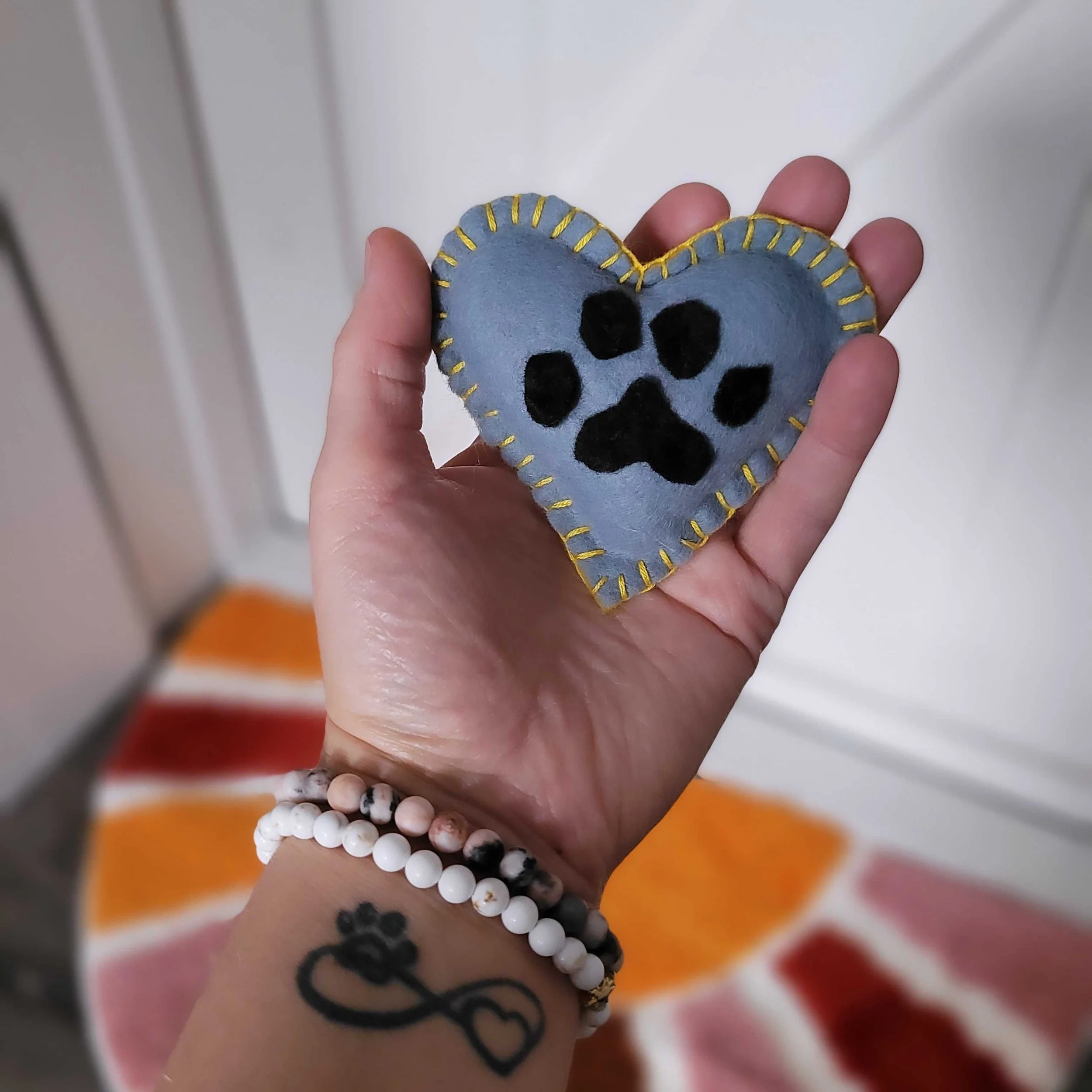Dr. Erica holding a pet loss heart, small handmade felt heart with a paw print on it representing the bond, the life, and the love with a beloved angel pet