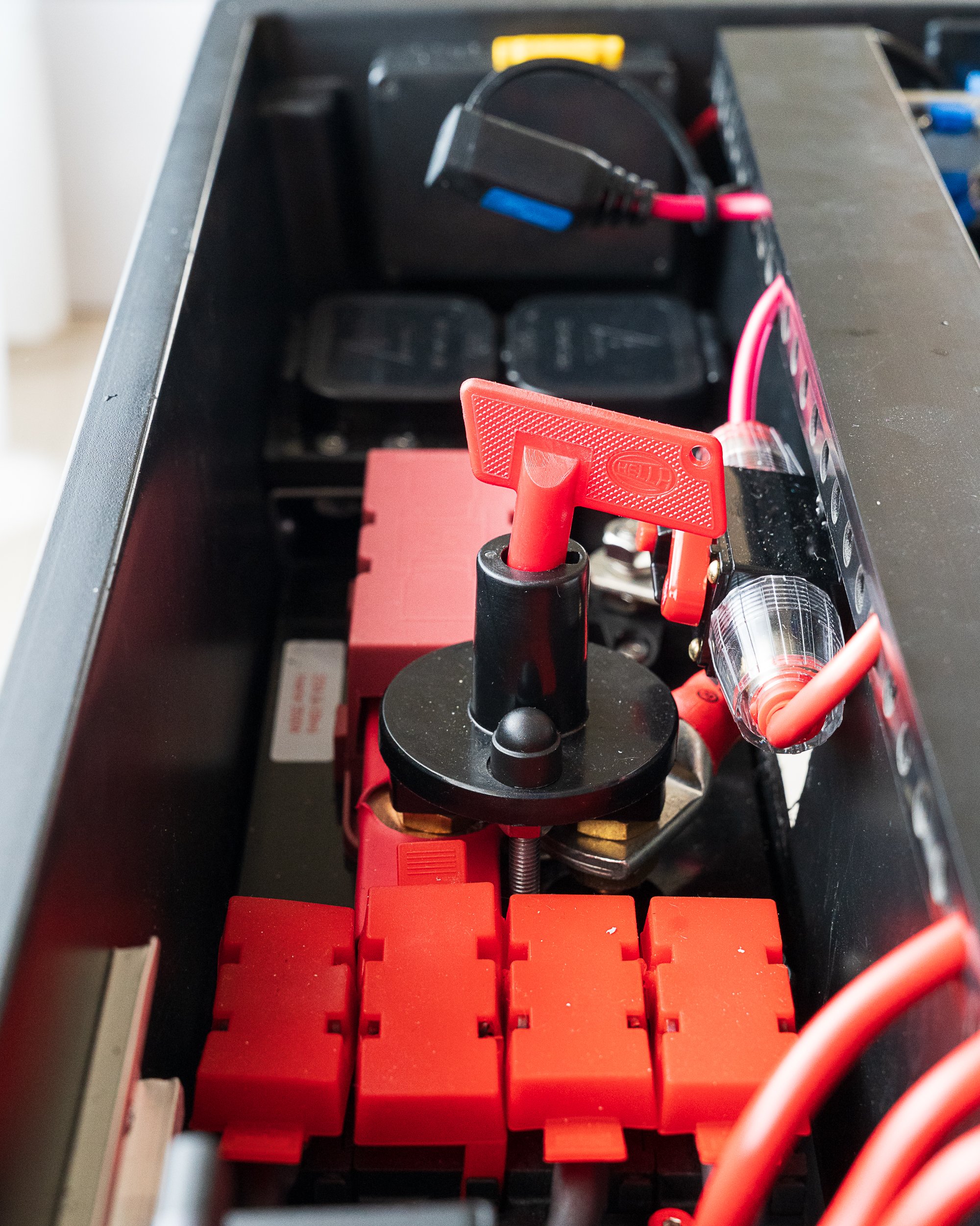 The main battery isolator with its red Hella key, flanked by heavy MEGA fuses protecting the primary cables.