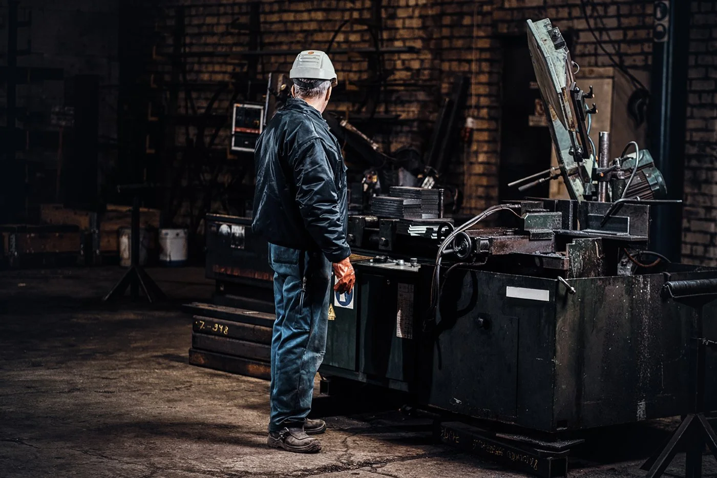 A worker in a dark industrial workshop operating heavy machinery.