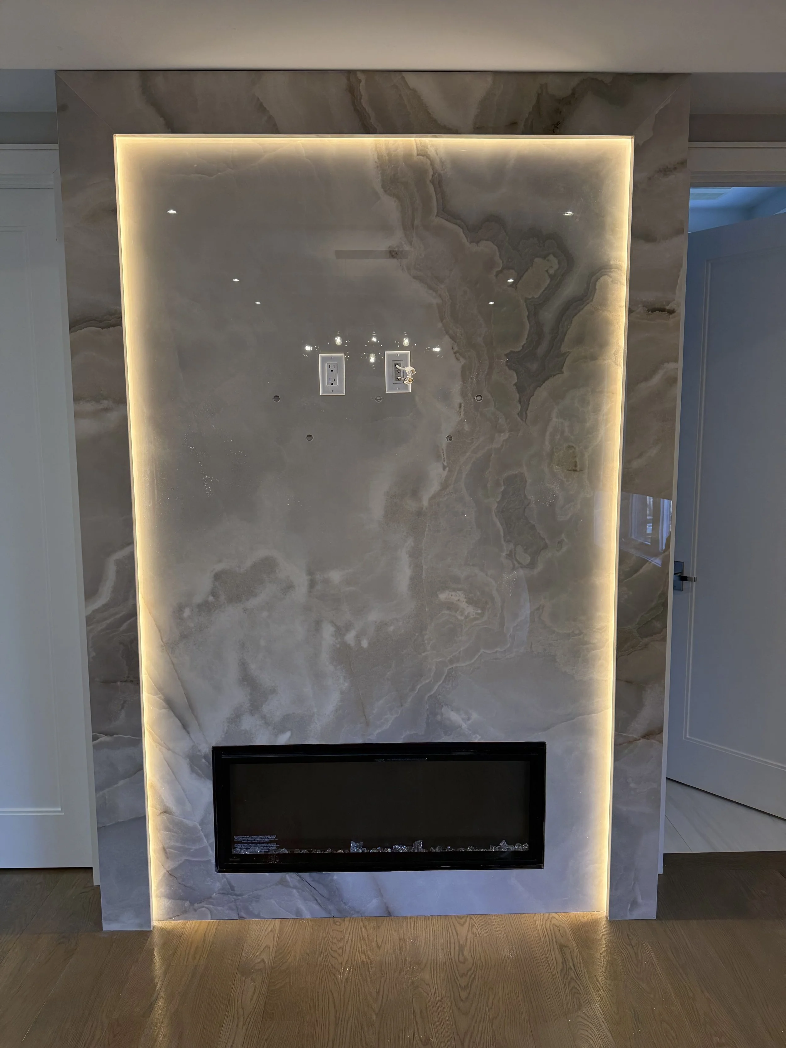 Marble fireplace with LED backlighting, two electrical outlets, and floor beneath.