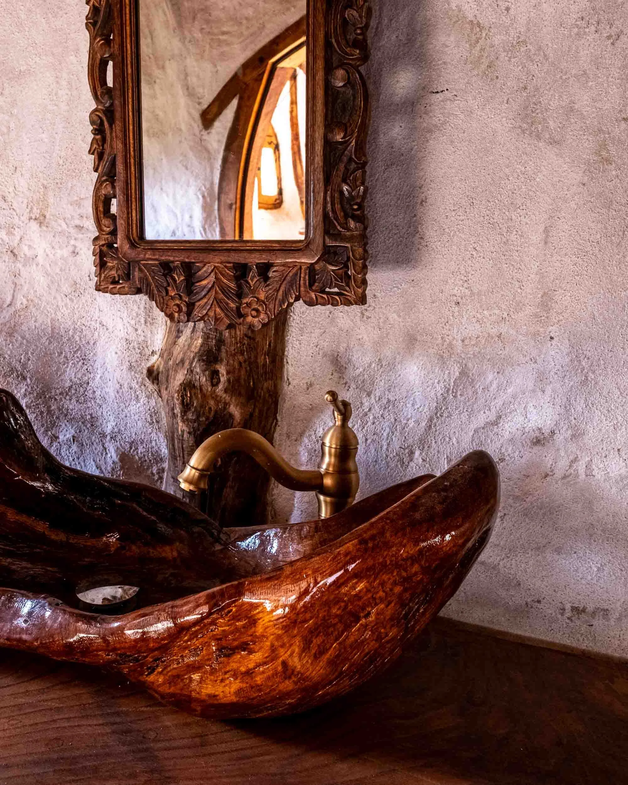Lavabo de piedra artesanal en baño de bioconstrucción con paredes de barro y acabados naturales