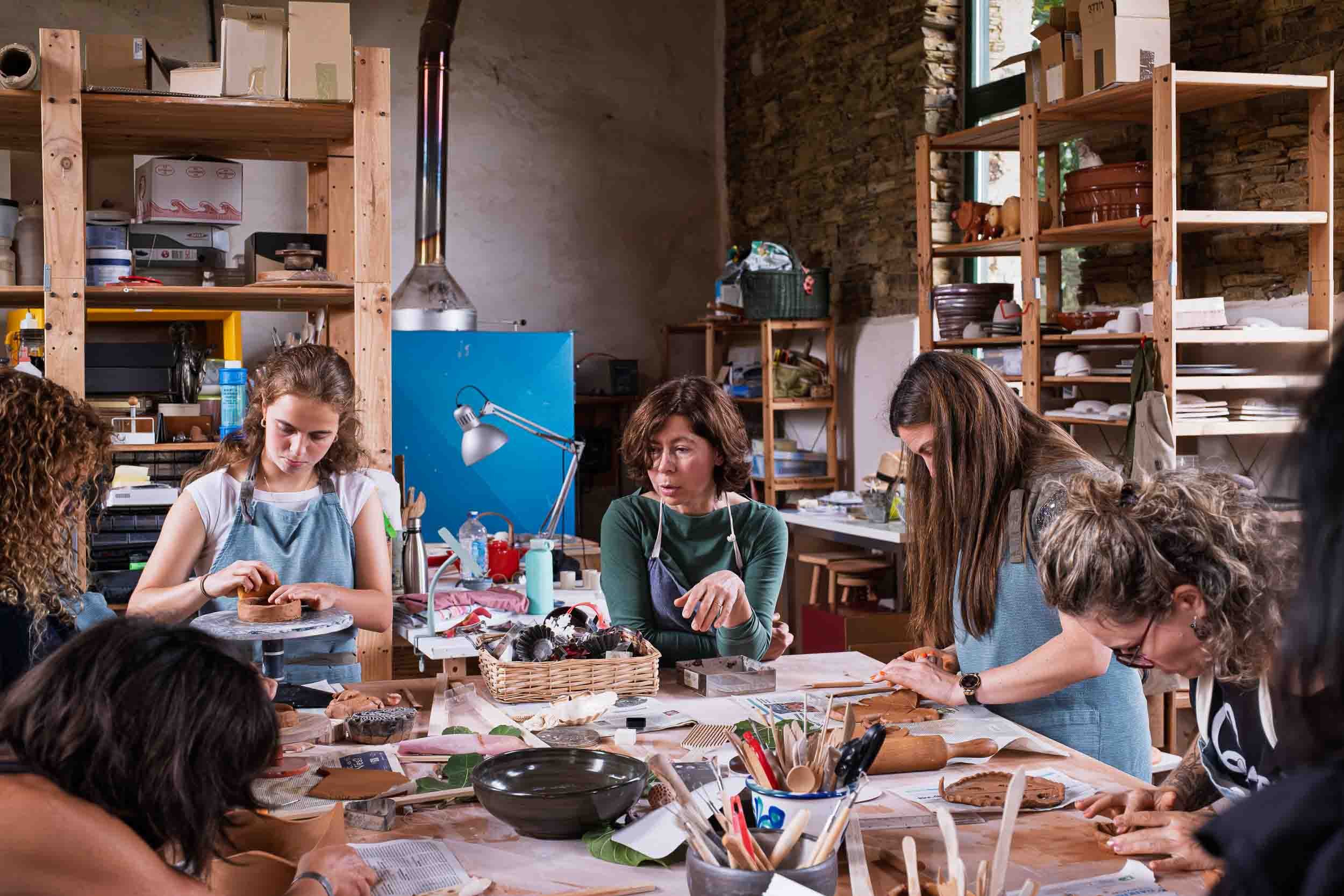 Perspectiva del taller durante una clase de alfarería con piezas de cerámica en diferentes estados.