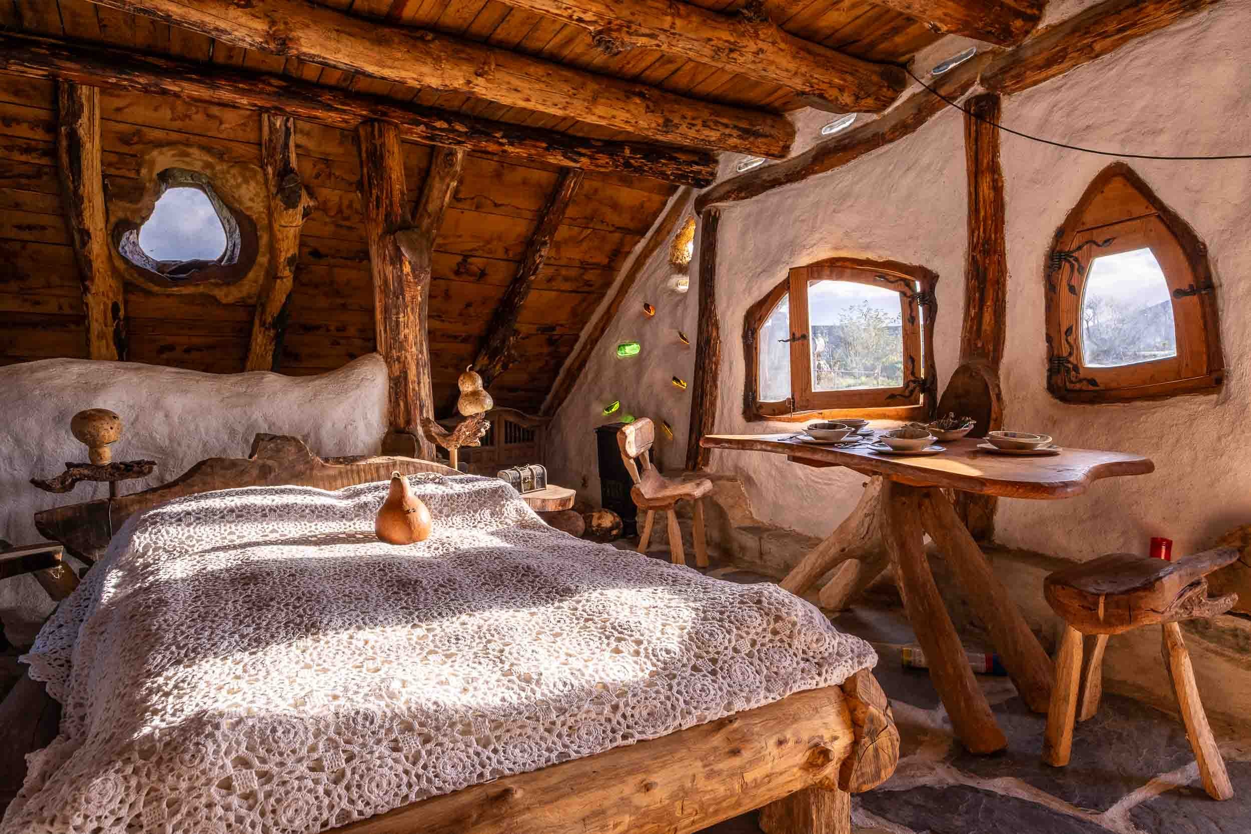 Dormitorio acogedor con paredes curvas de barro y paja, creando un ambiente de refugio natural.