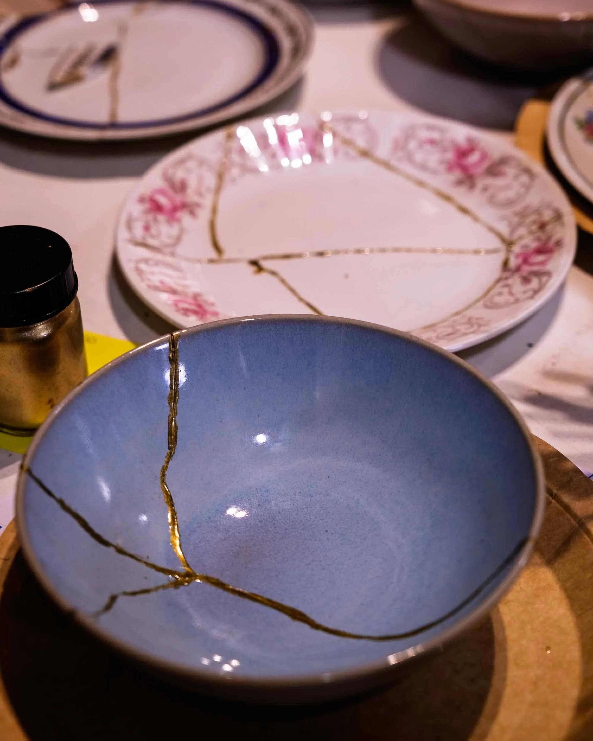 Vajilla de cerámica con grietas reparadas mediante la técnica estética del Kintsugi con resina de oro.