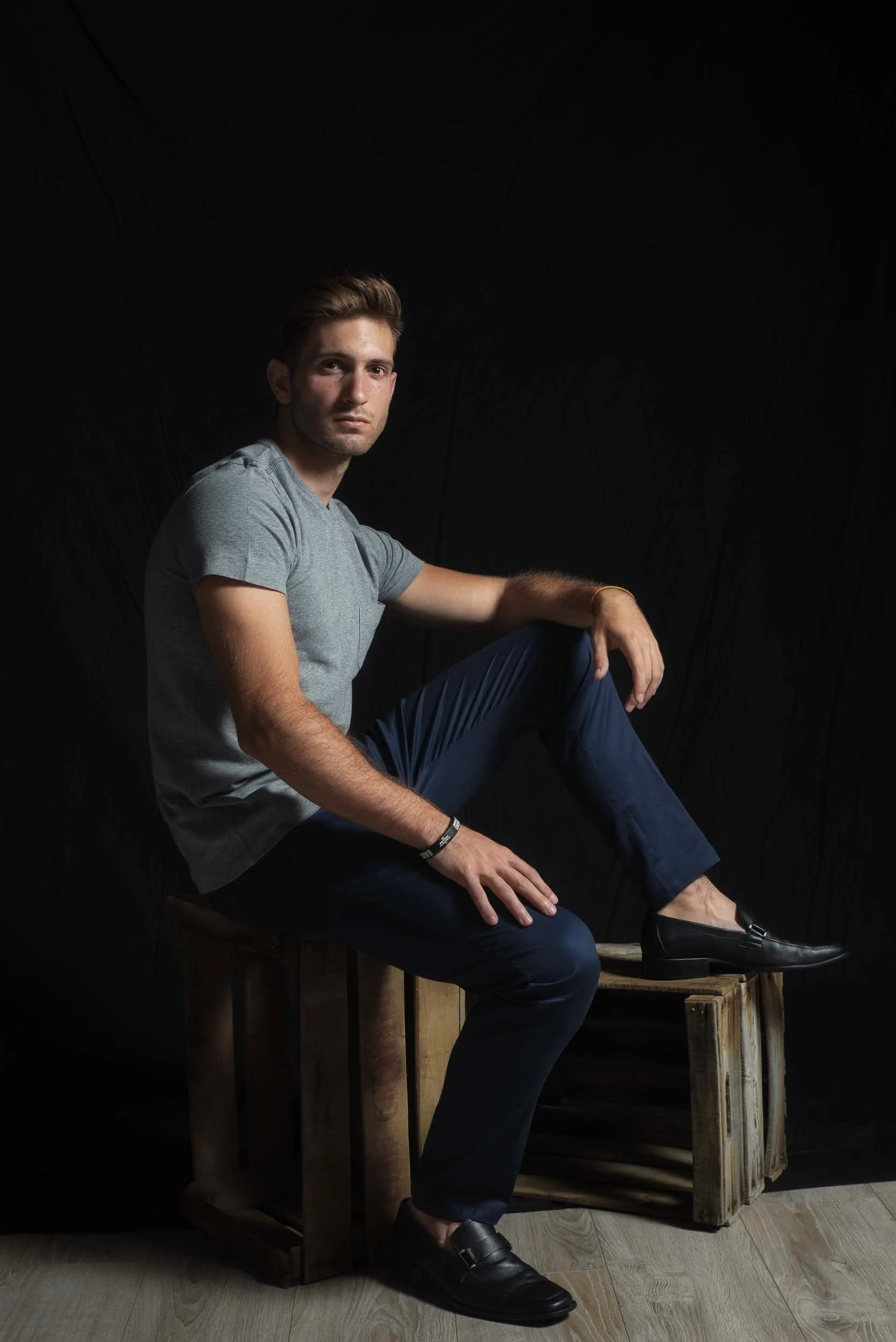 Retrato de joven con mirada intensa sentado sobre cajas de madera de fruta, estilo rústico y personal, fotografía de territorio de Photorural.