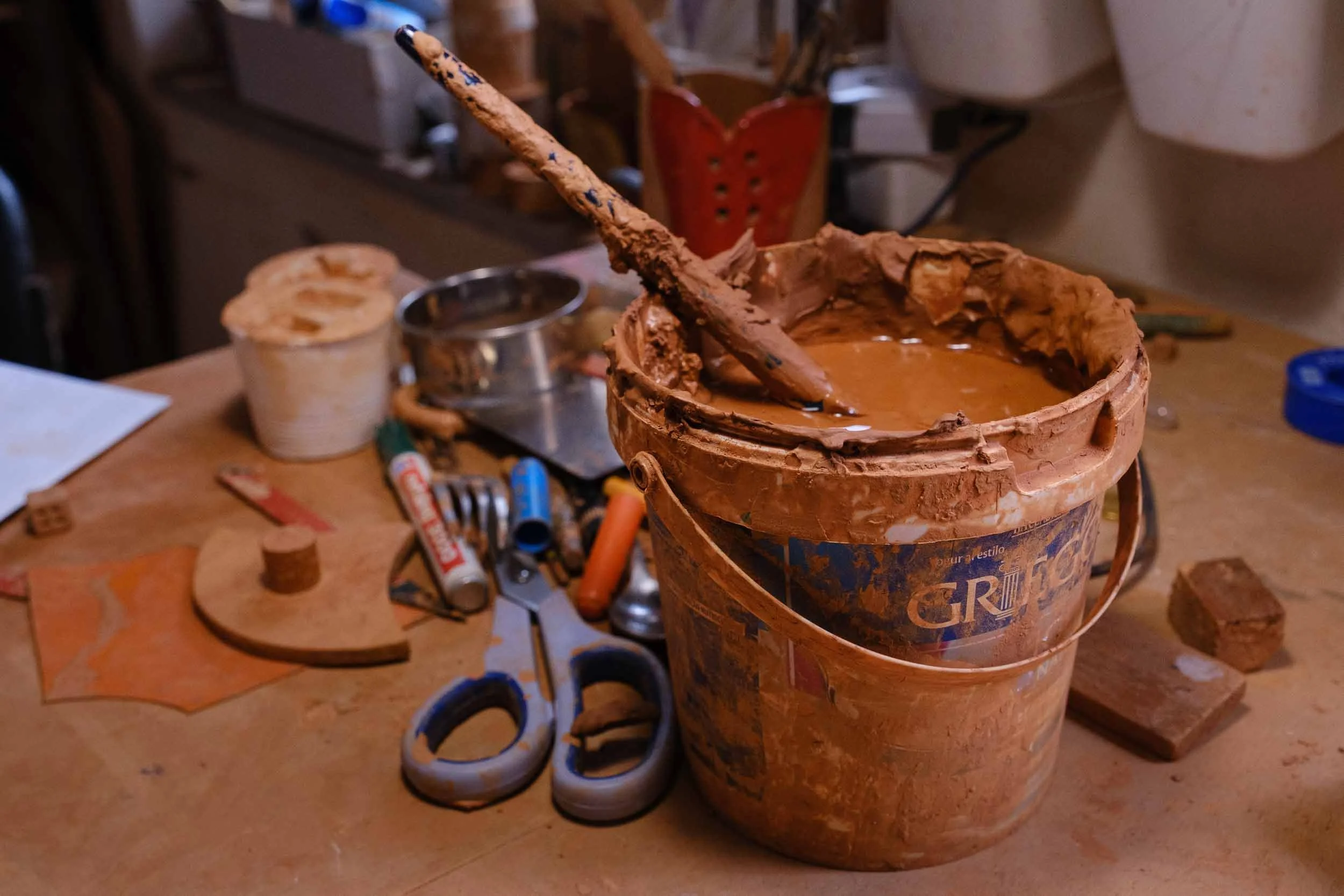 Detalle de un cubo con mezcla de engobe de barro y pinceles en un taller de cerámica artesanal.