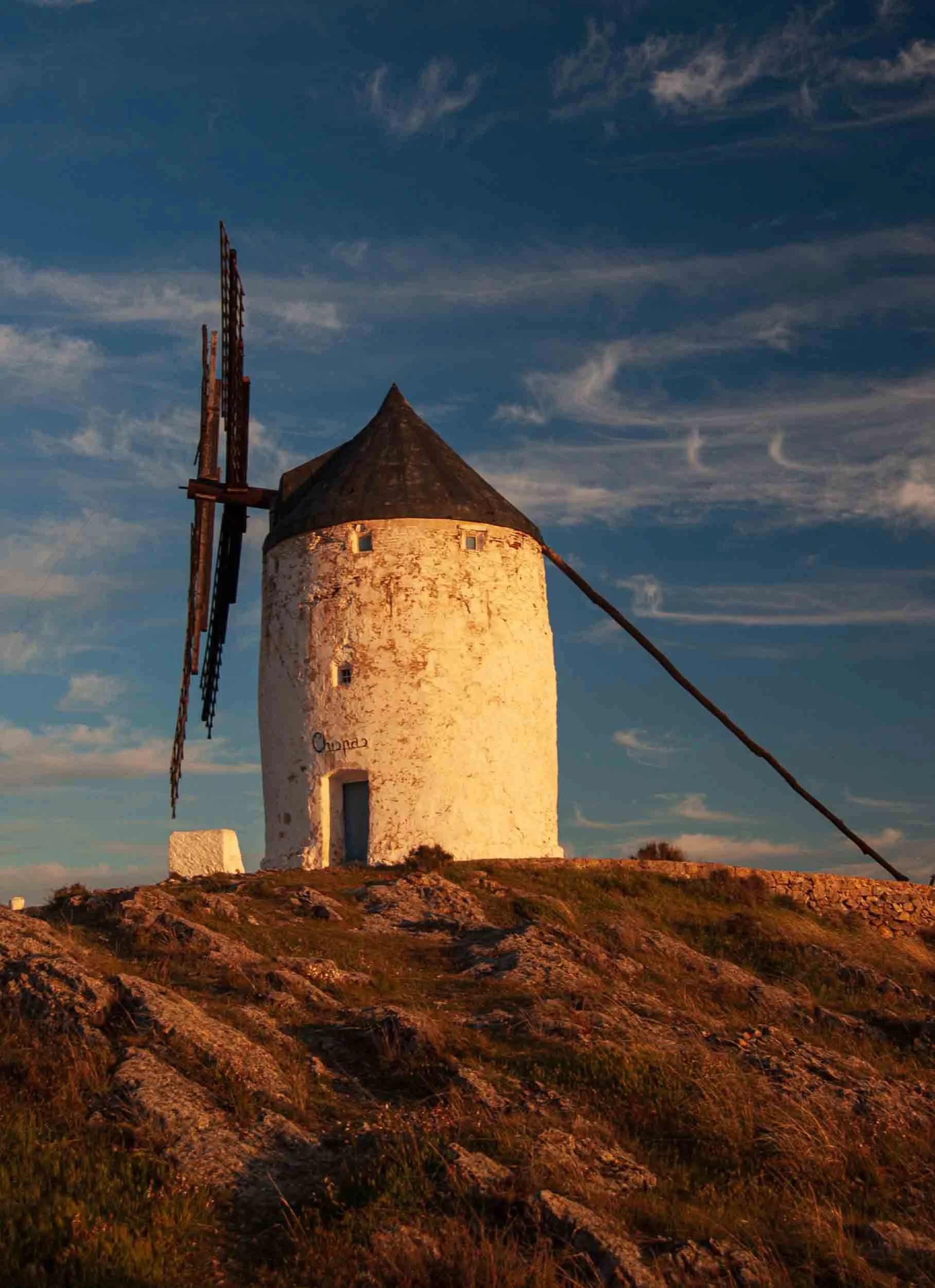 Molino de viento tradicional en Castilla-La Mancha bajo un cielo despejado, icono de la arquitectura rural española.