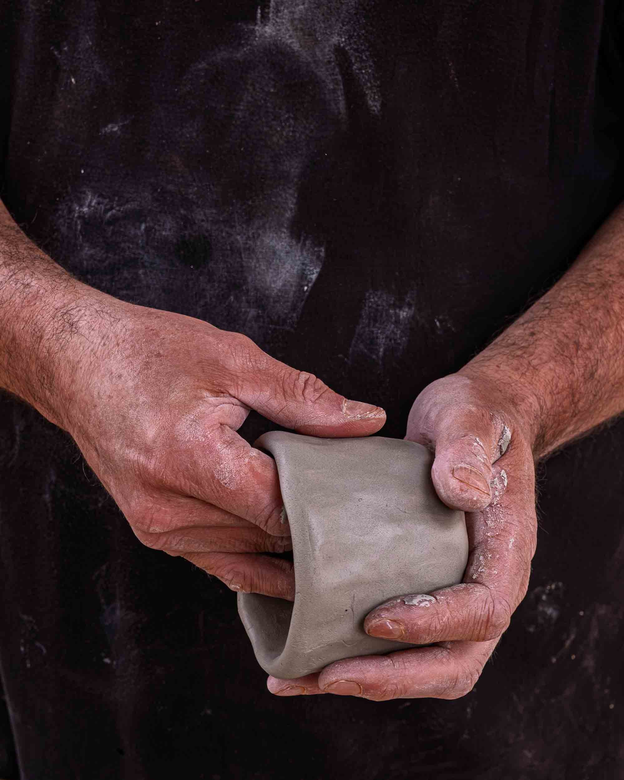 Retrato del maestro alfarero Marcelo concentrado mientras modela una pieza con sus manos.