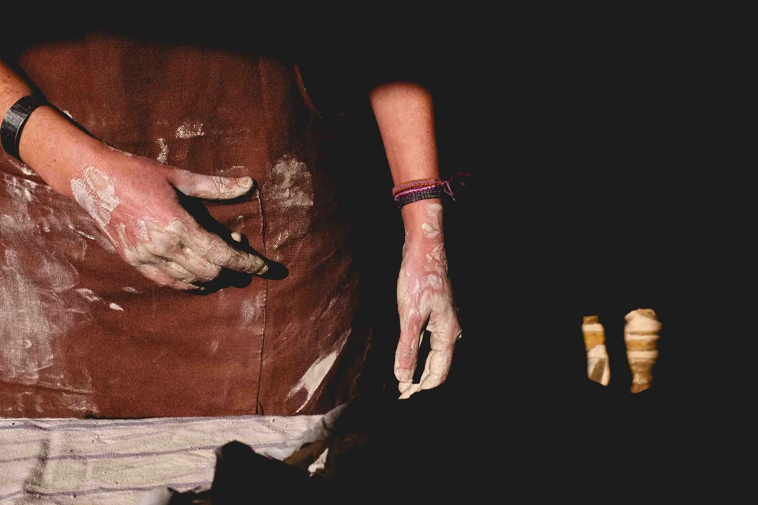 Un primer plano de las manos de la artesana de Arenaysal, mostrando la textura y las herramientas manuales, simbolizando la sabiduría y el oficio manual.