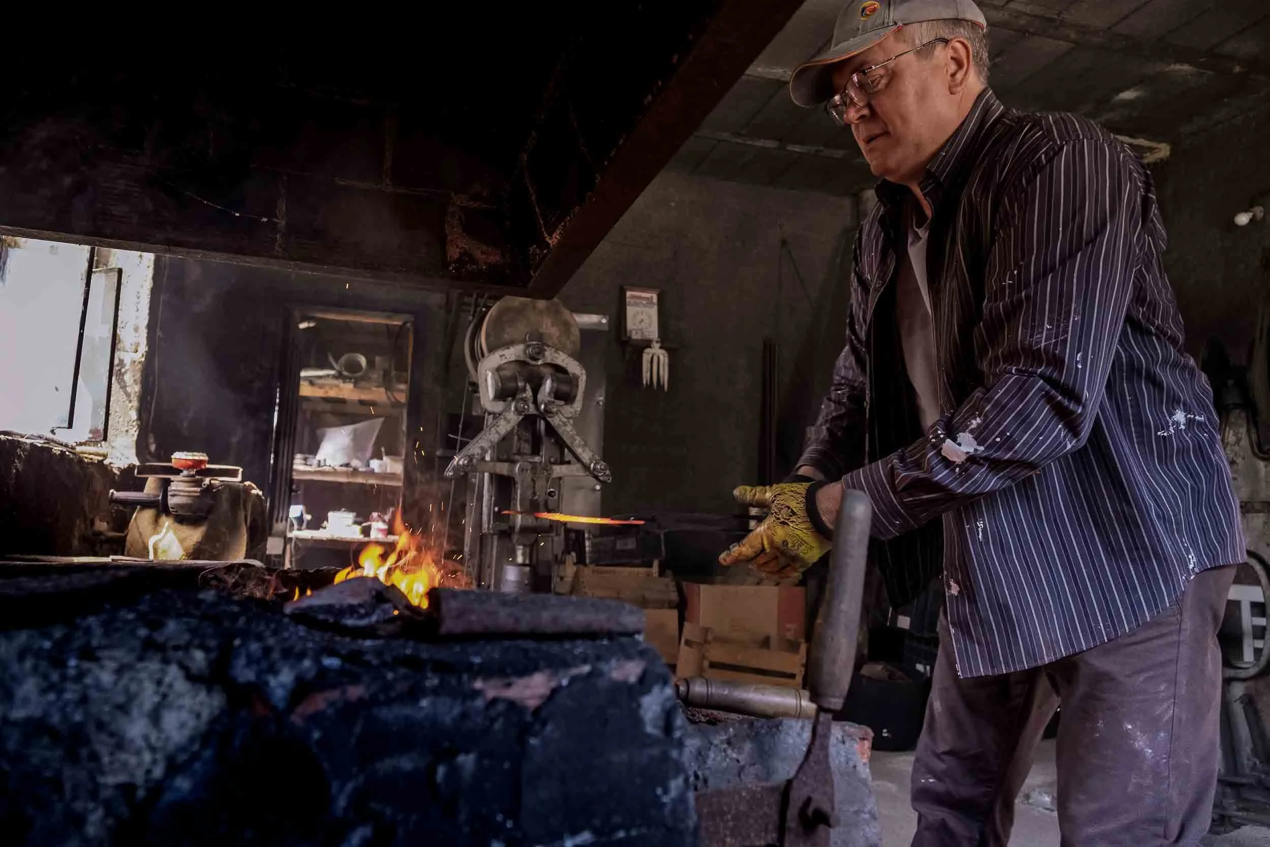 El ferreiro manejando las tenazas para calentar el hierro en el corazón de la fragua de carbón.