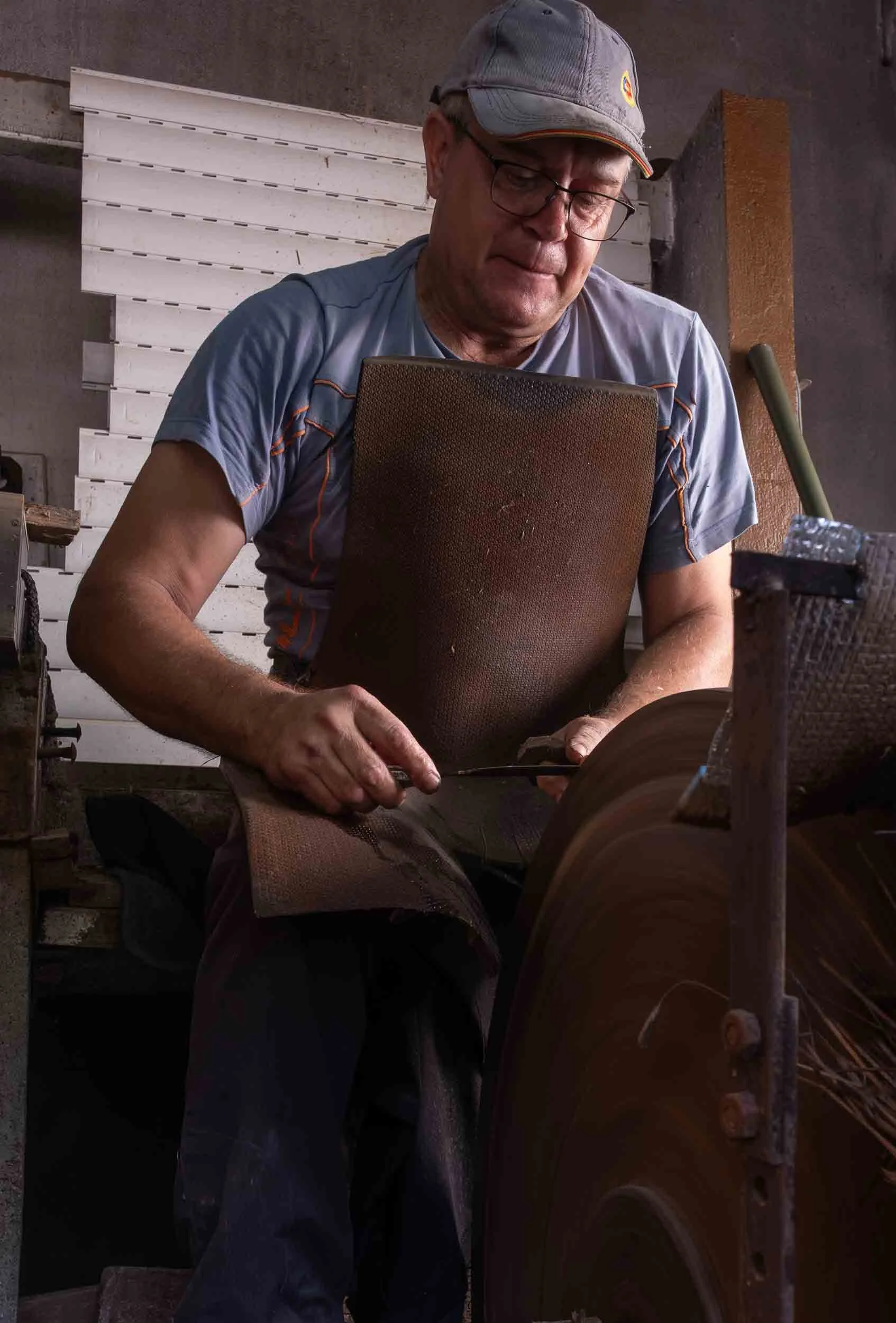 Artesano ferreiro de Riotorto dando filo a una herramienta de corte en la piedra de afilar