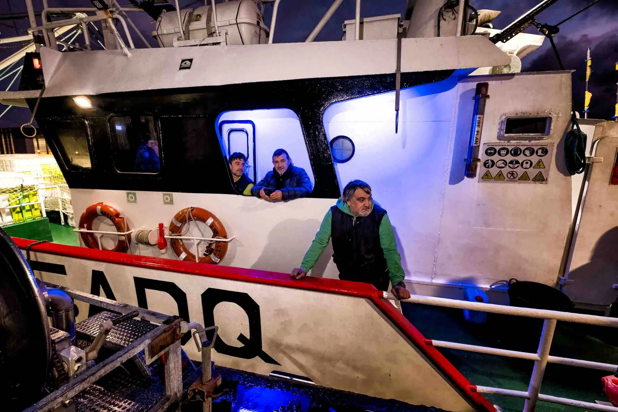 Patrón en el exterior del puente de mando del Breso Uno  verificando las labores de descarga de merluza en la lonja de Burela.