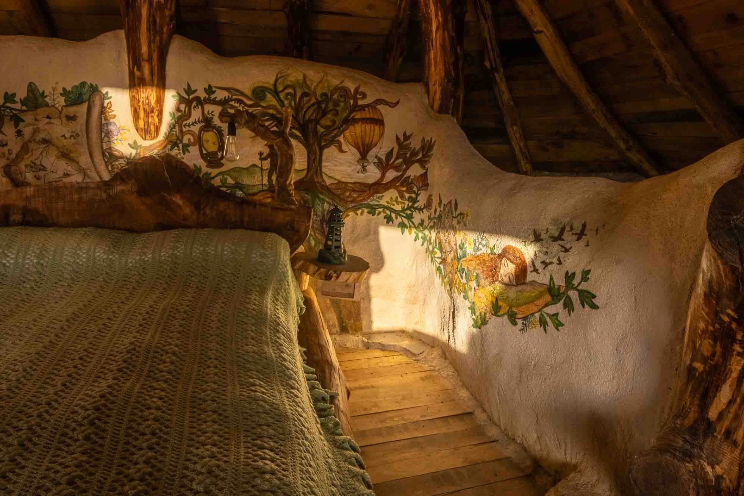 Dormitorio acogedor con paredes curvas de barro y paja, creando un ambiente de refugio natural.