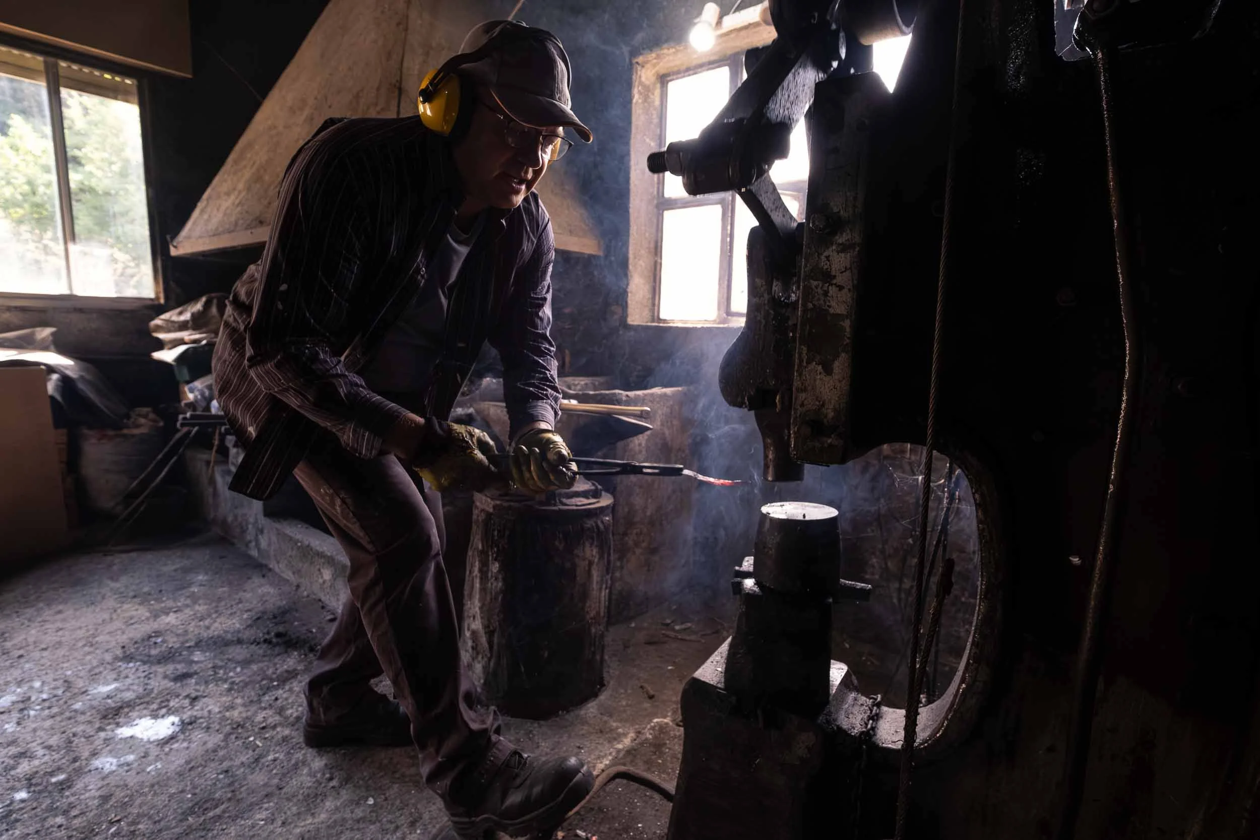 Un maestro ferreiro operando con precisión el mazo sobre una pieza de hierro en el yunque.