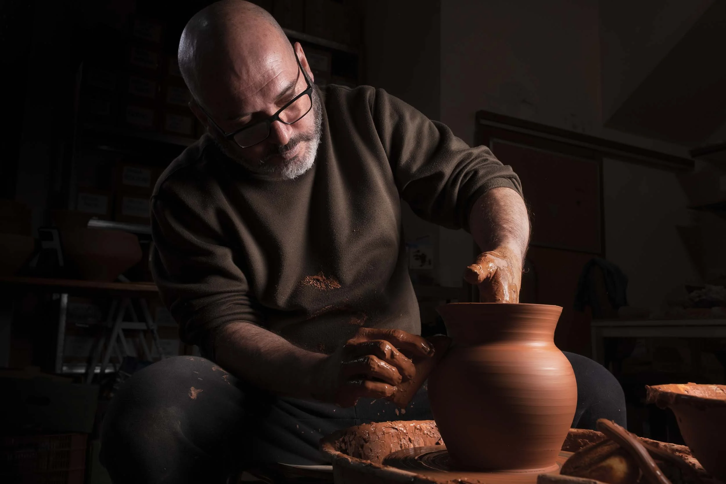 Un alfarero torneando una pieza de cerámica en su taller tradicional. La imagen muestra el entorno auténtico del alfar en Mondoñedo.