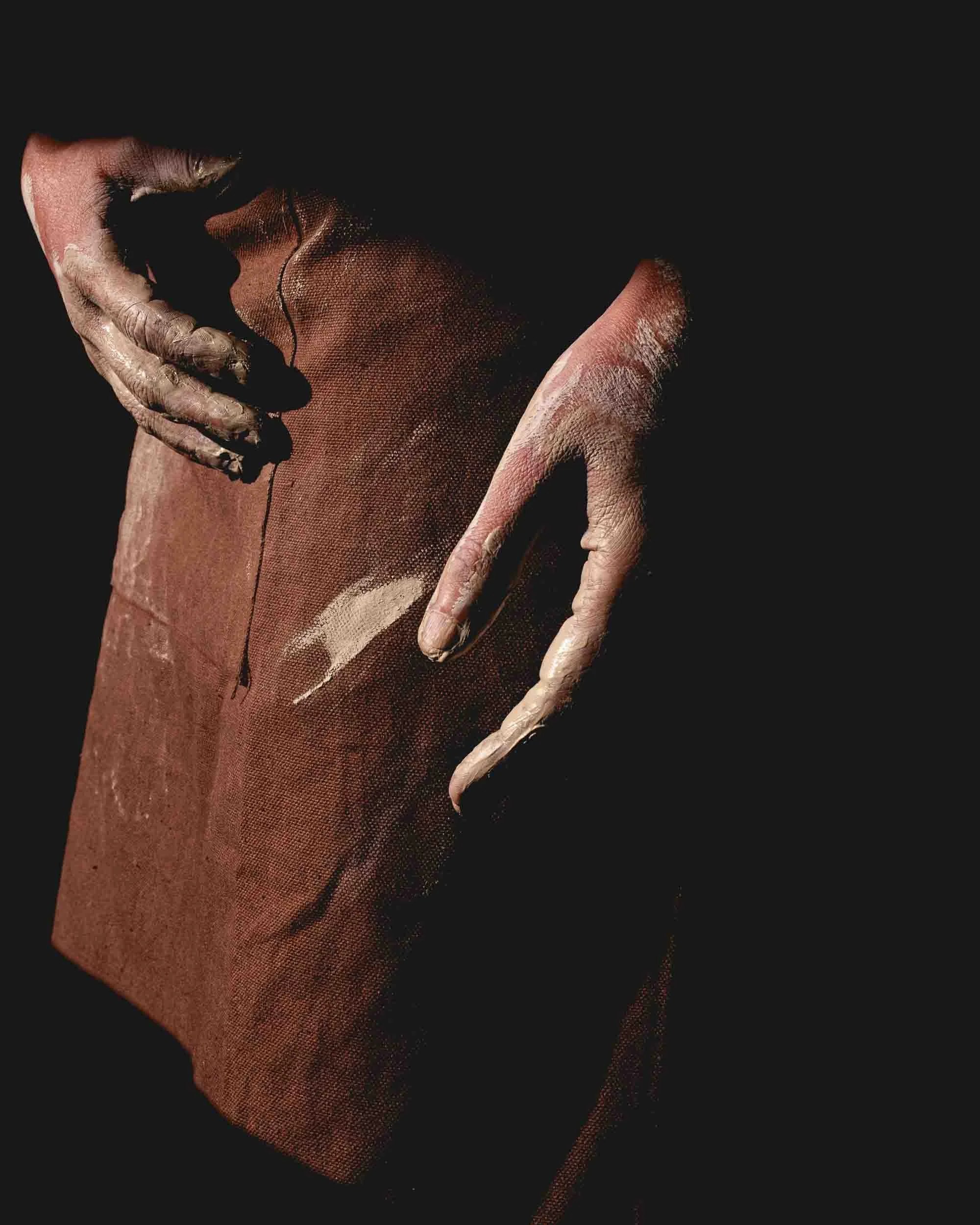 Primer plano detallado de las manos de la artesana de Arenaysal moldeando barro crudo, capturando la conexión táctil primaria con la materia.