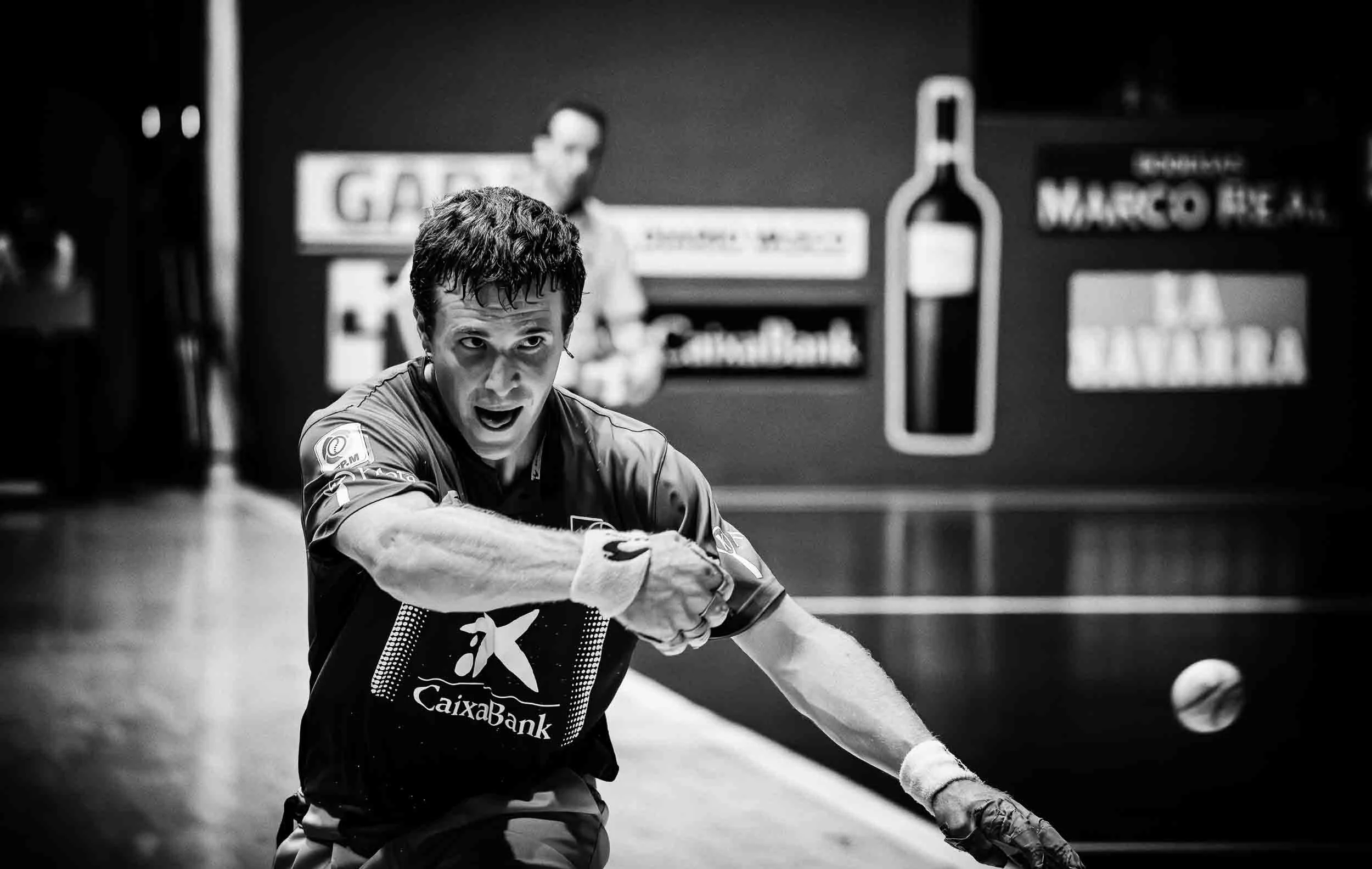 Acción de juego de pelota vasca en un frontón tradicional de piedra, capturando el movimiento y la esencia del deporte rural vasco.