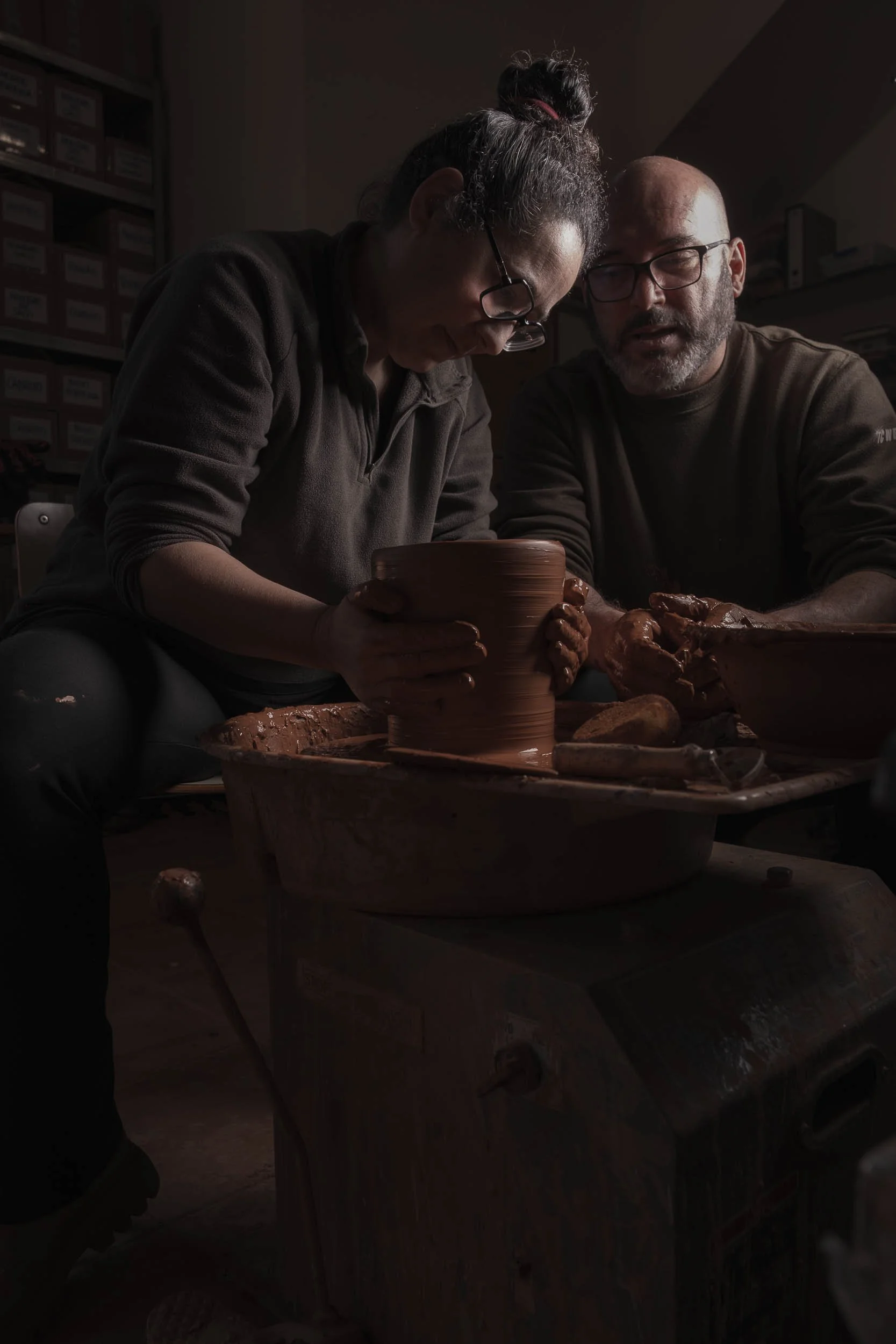 Maica y Marcelo, alfareros de Esquina Atlántica, trabajando simultáneamente en sus tornos. Refleja la colaboración y la tradición compartida.