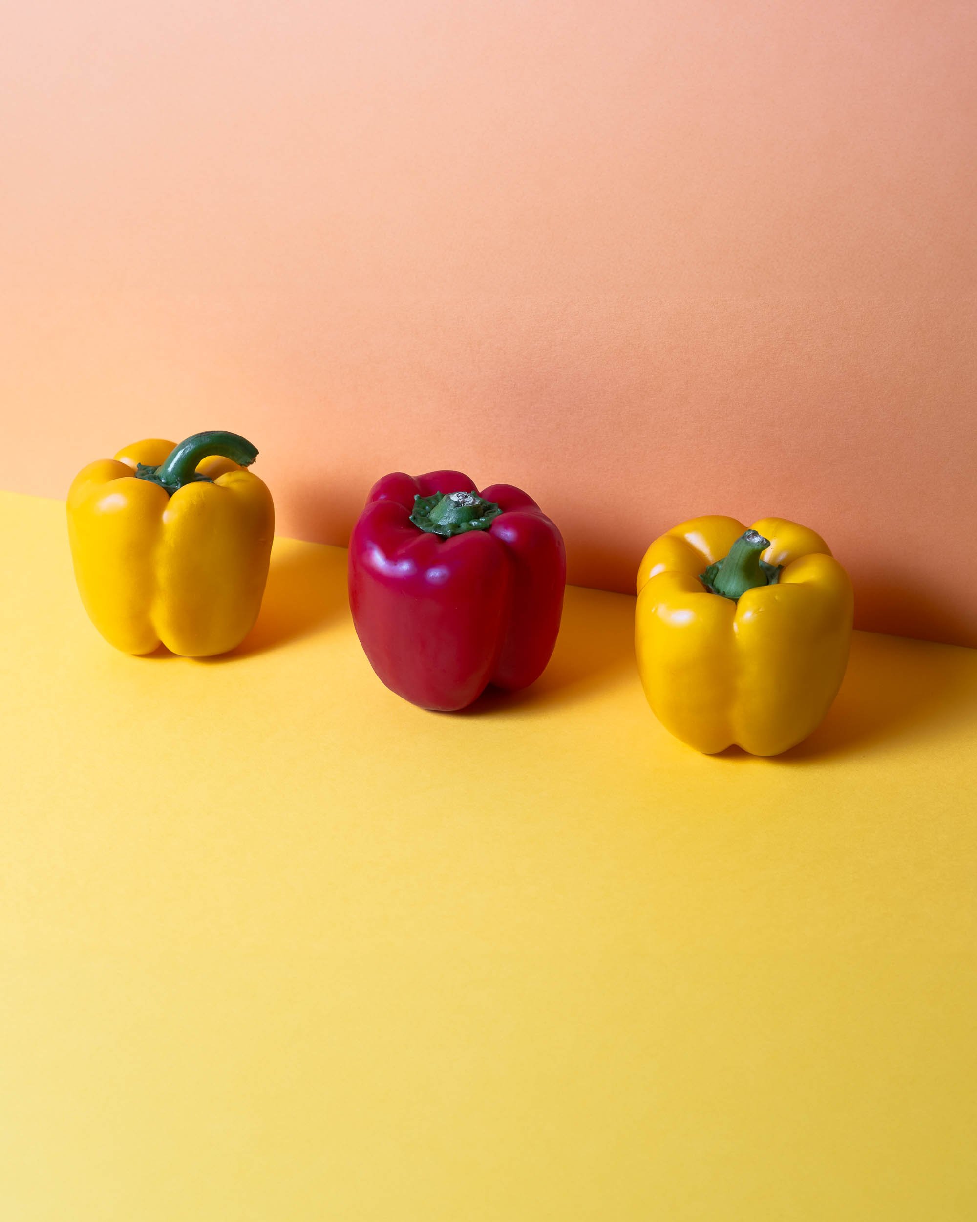 Retrato de estudio de pimientos frescos, resaltando el brillo de la piel y la intensidad del color bajo iluminación profesional de Photorural.