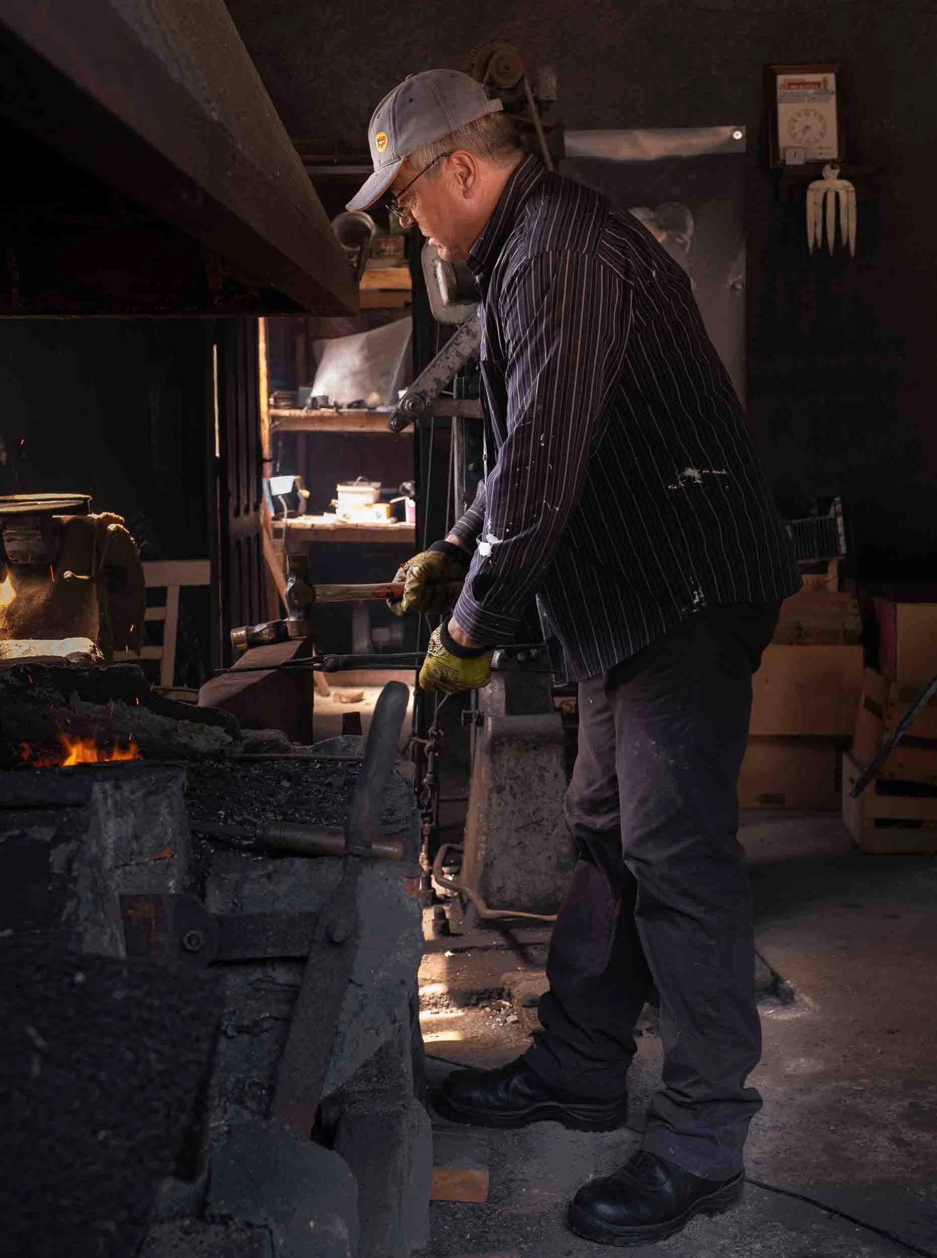 El artesano ferreiro realizando el proceso de temple del hierro incandescente para dar dureza al metal.
