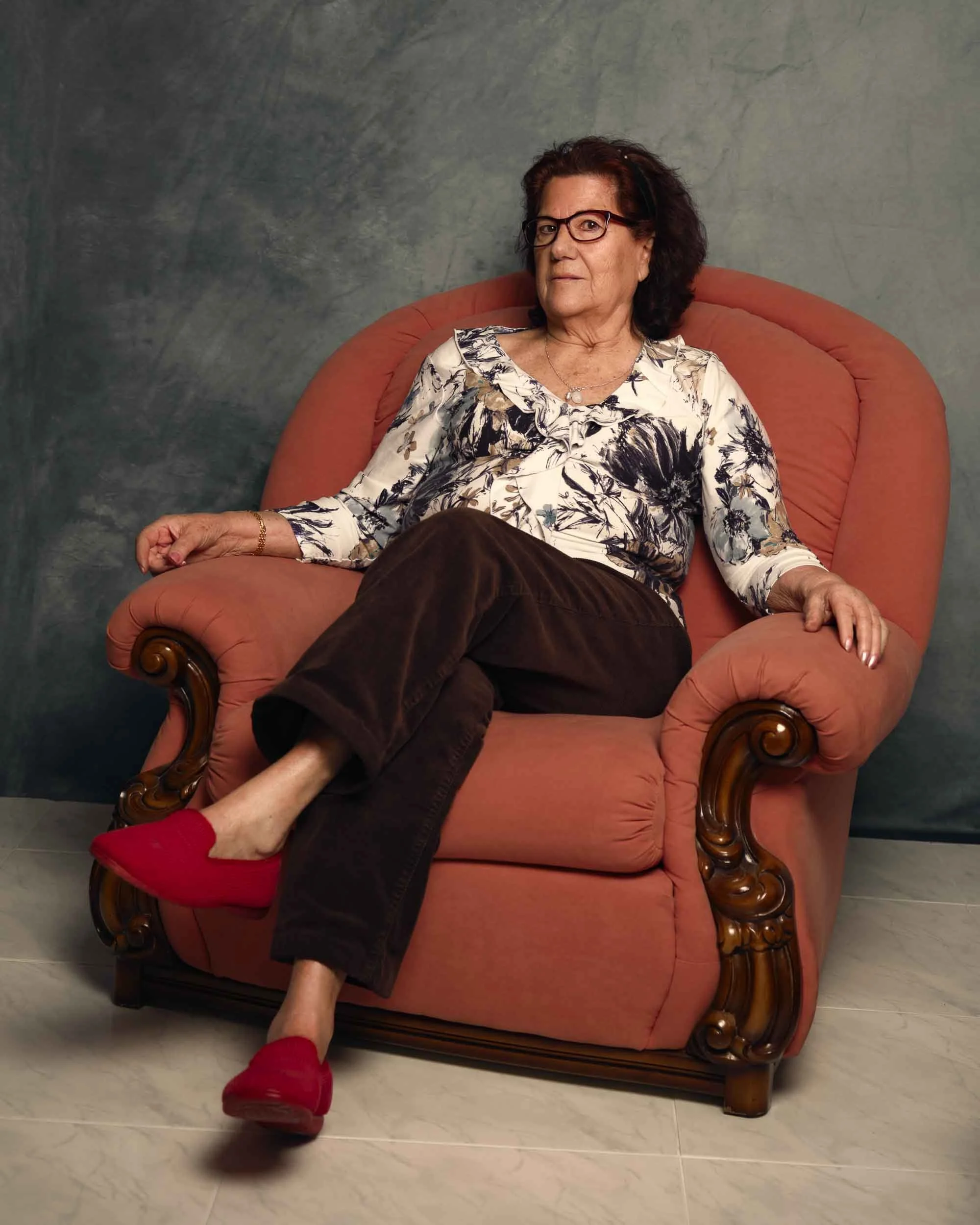 Mujer mayor posando con ropa de casa en su sillón, retrato íntimo y auténtico de la vida cotidiana en el rural por Photorural.