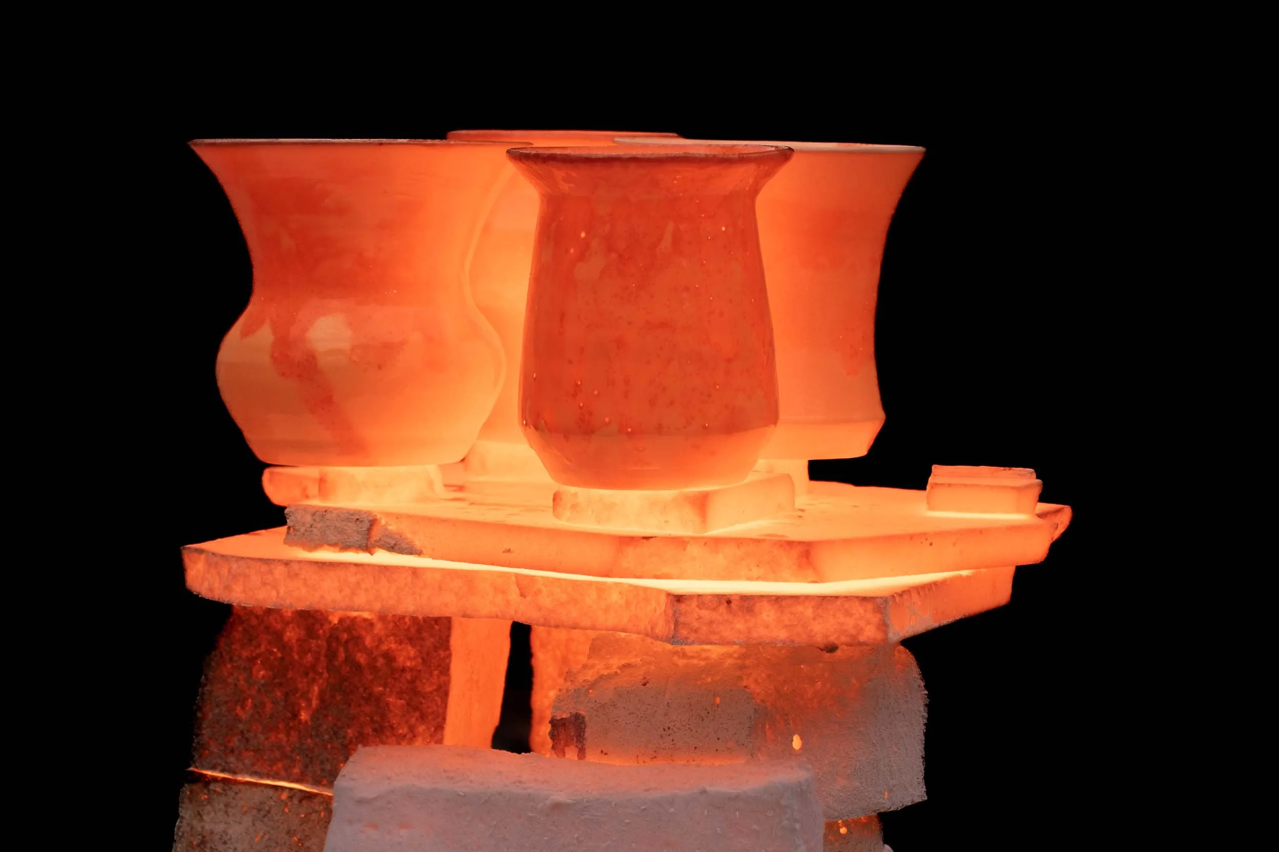 Piezas de cerámica al rojo vivo dentro de un horno de Raku durante el proceso de cocción artesanal