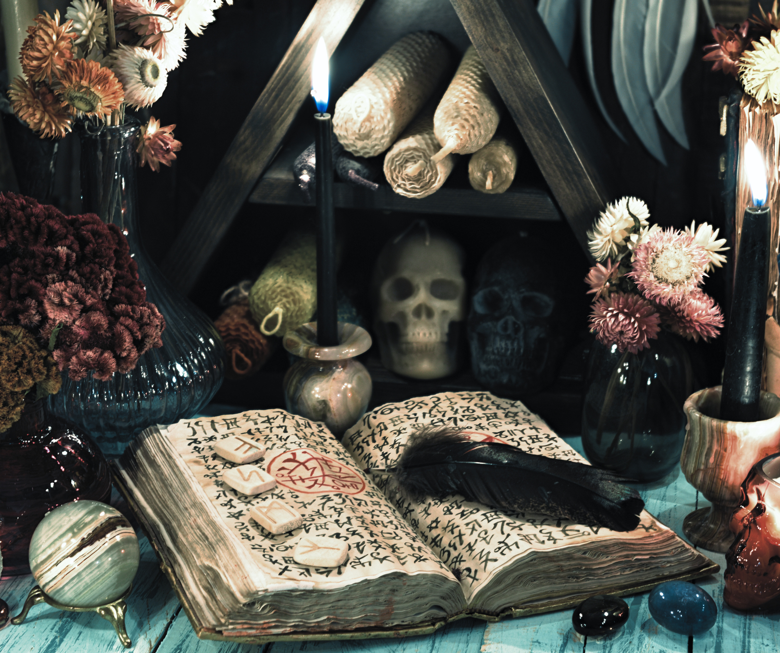 A dark altar with a skull, open book with strange symbols, and candles surrounded by flowers and stones, creating a mystical ambiance.
