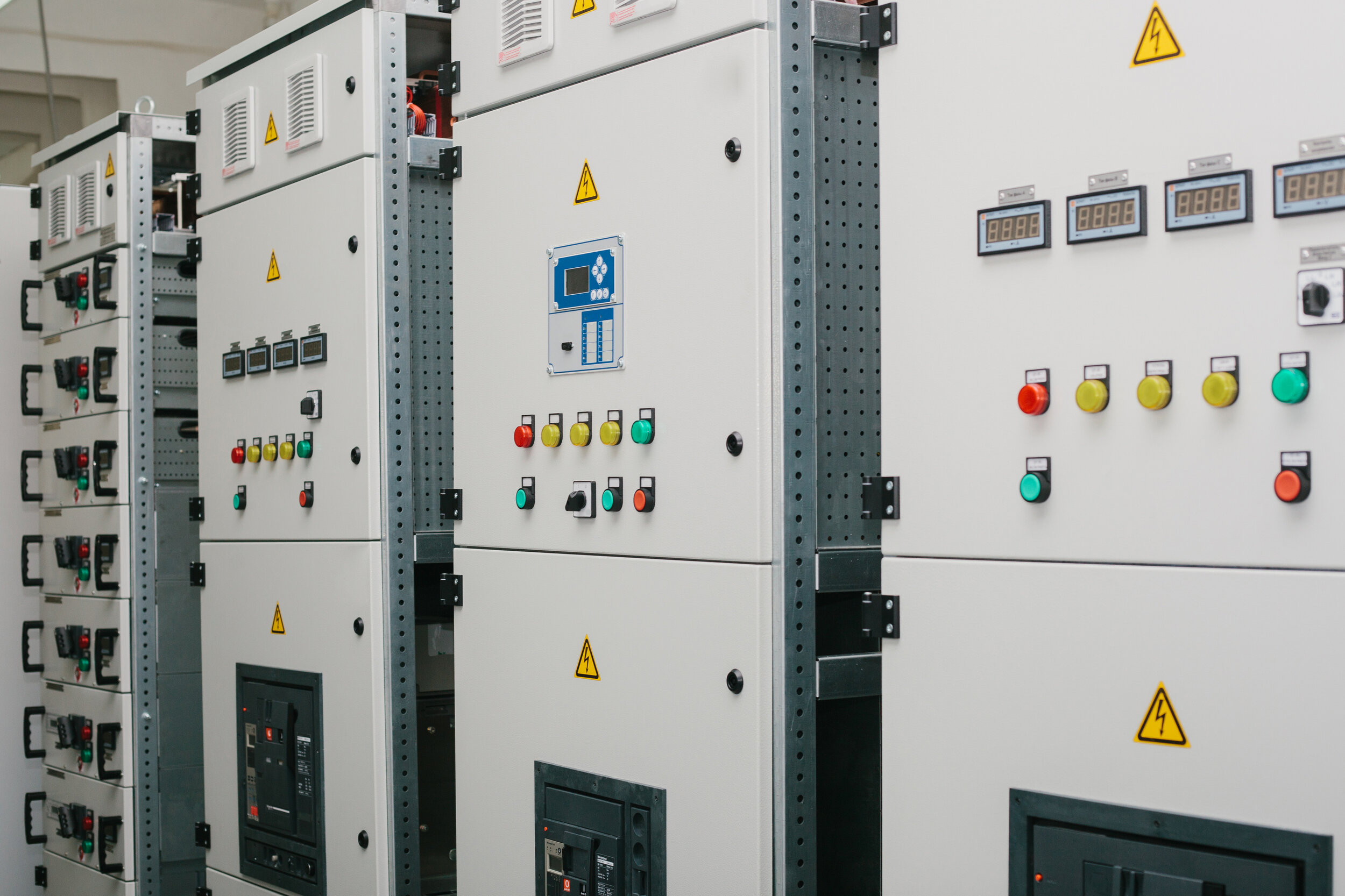 Electrical control panels with warning signs and various switches, buttons, and digital displays.