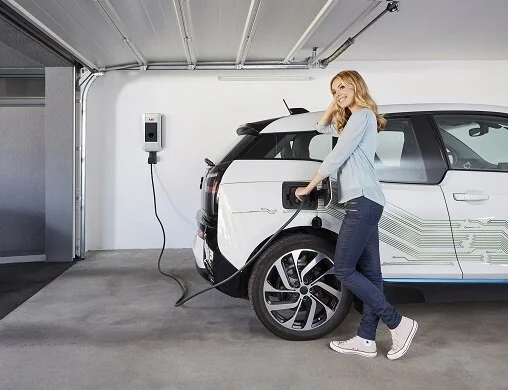 A woman charging an electric car in a garage.