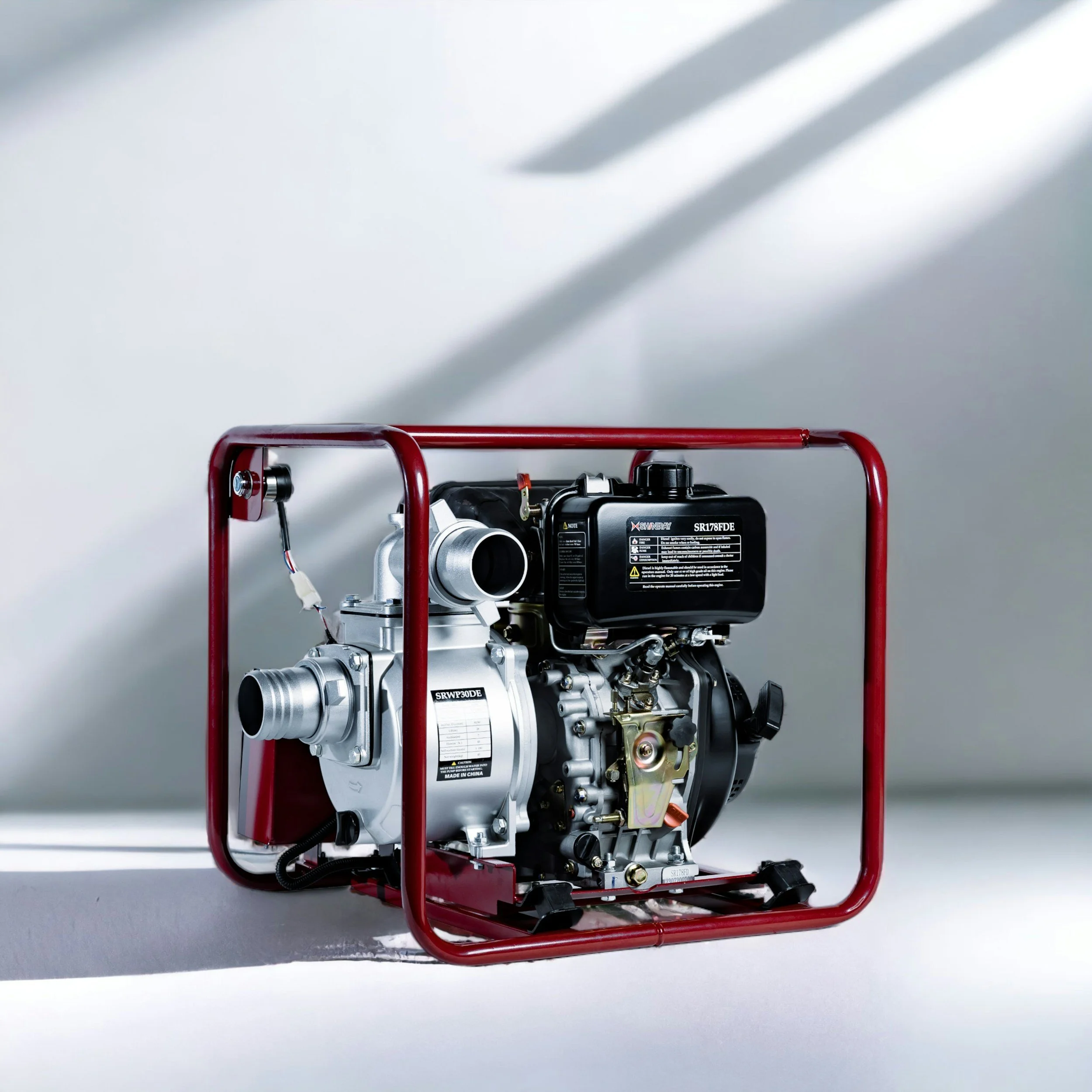 Portable fire pump with red metal frame, black engine, and silver metal components, placed on a white surface with a light gray background.