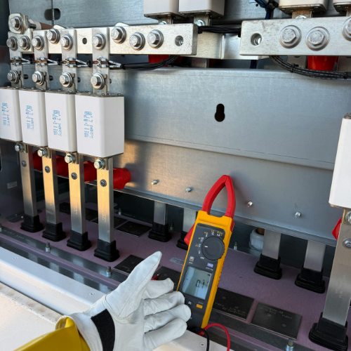 Close-up of electrical panel with multimeter testing a circuit, operator wearing gloves.