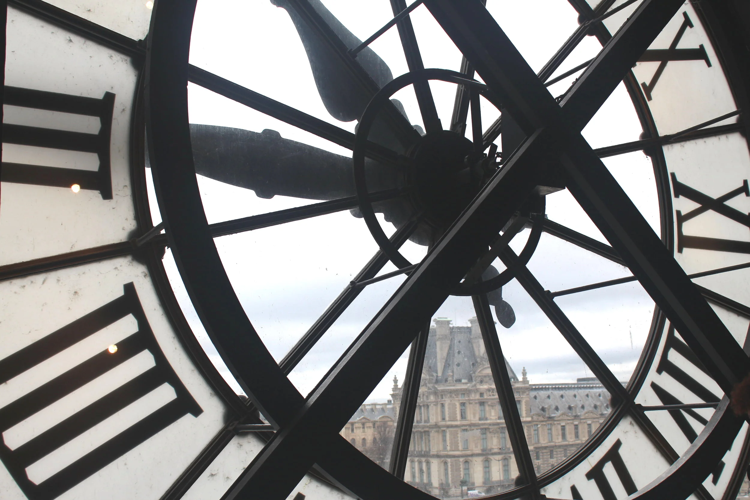 View through the famous Musée d'Orsay clock overlooking Paris and the Louvre Museum.