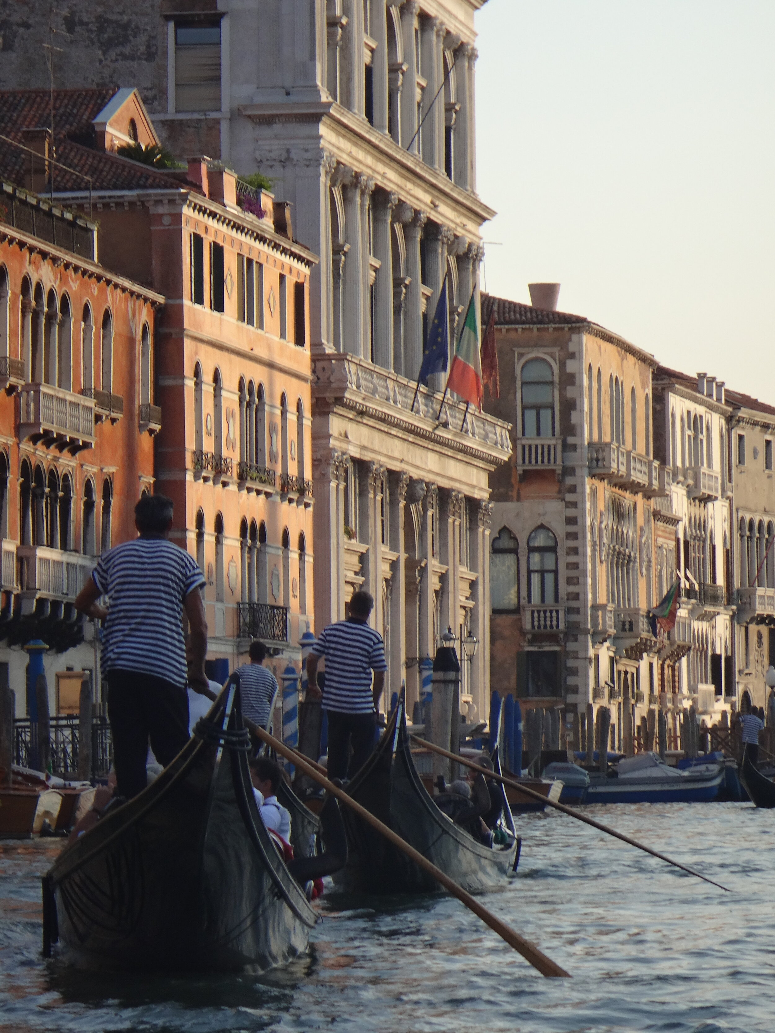 Gondoliers rowing passengers past historic buildings in Venice, Italy