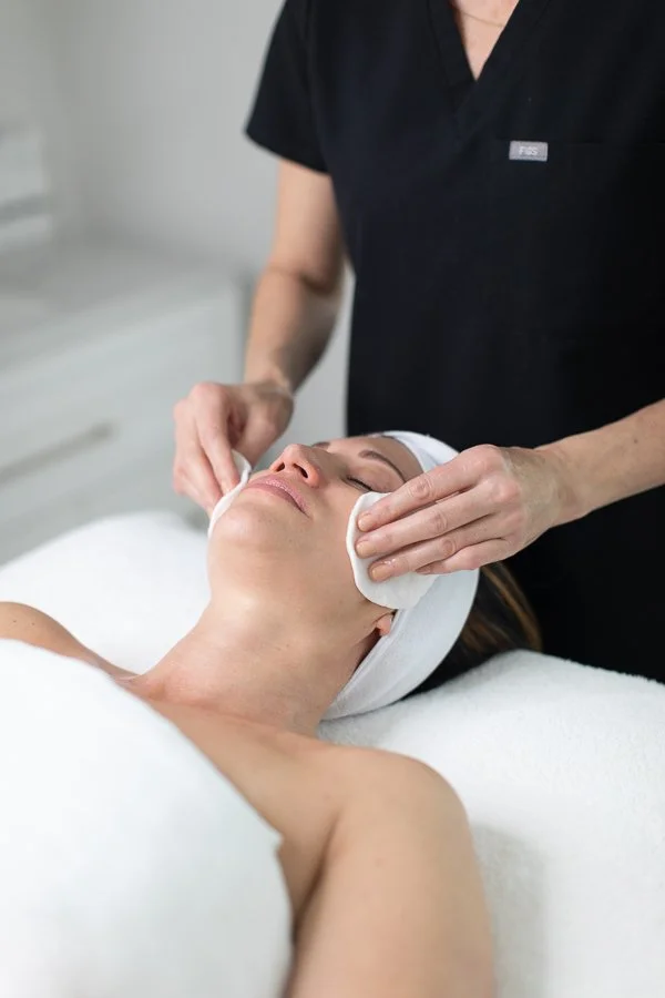 A woman receives a chemical peel treatment at Atelier Skin spa, with skincare professional Betsy Tomasello.