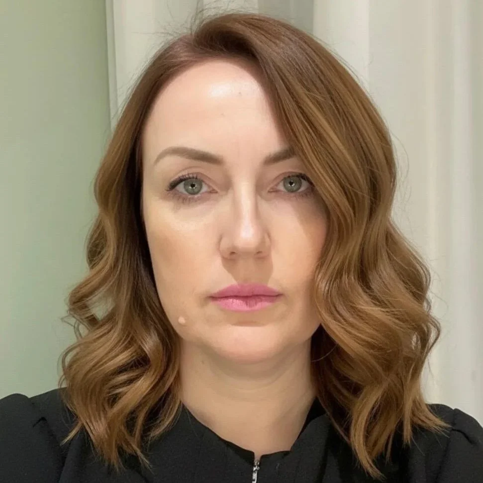 Nainen katsoo kameraan, takana pehmeät valkoisen ja vihreän sävyiset kasvit. Parturi-kampaaja Elena, Shortcut TELAKKARANTA