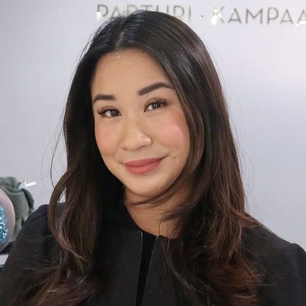 Nainen katsoo taaksepäin kameraan, taustalla vaaleanvärinen seinä. Parturi-kampaaja Le, Shortcut LAUTTASAARI