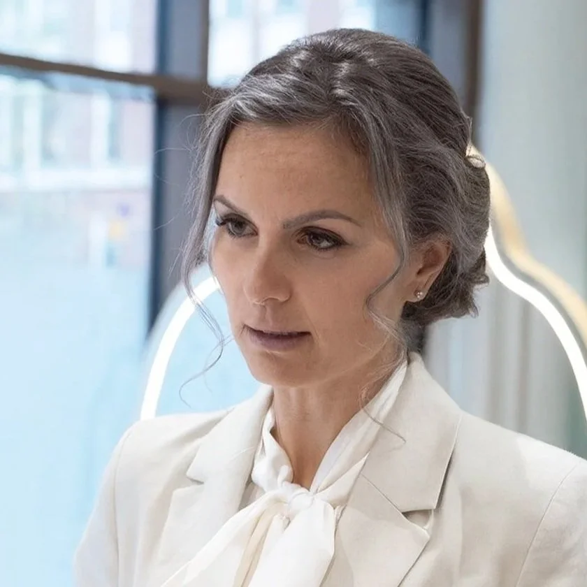 Nainen istuu ikkunan vieressä, hymyilee, pitkät laineilevat hiukset, kukallinen paita, rannekello ja sormus, valkoinen seinätausta. Maria Mattsson, Shortcut-ketjun omistaja ja yrittäjä.