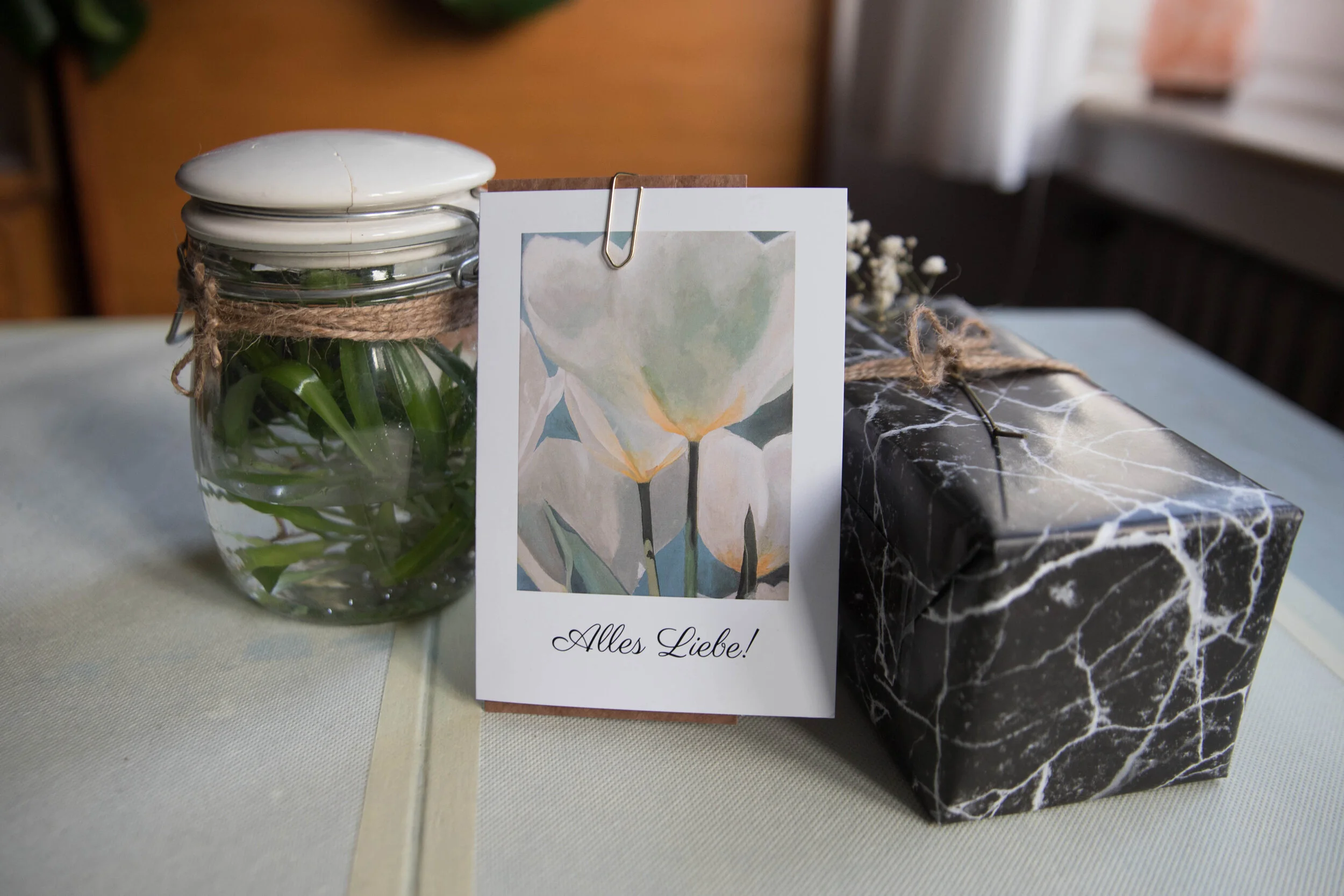 Nachher: Ableger einer Grünlilie in Wasser, eine selbstdesignede Karte und das (in einen Kaffeekapselkarton) verpackte Oberteil