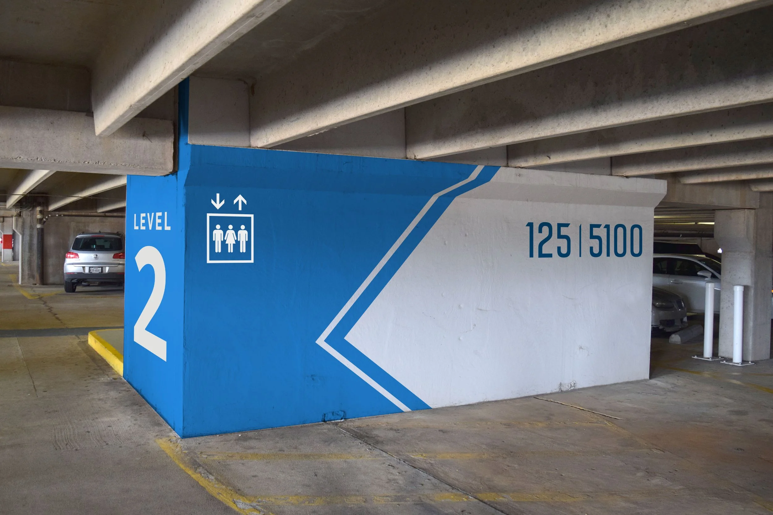 Bright blue directional elevator painted signage on concrete exterior opposite of the elevators for level 2