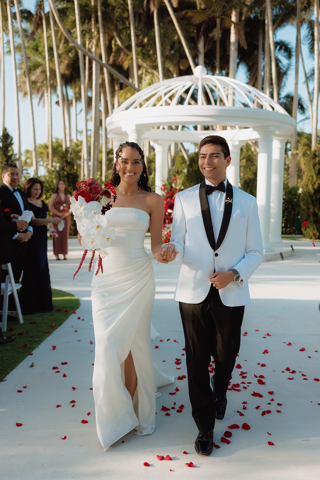 Bride holding an elegant cascading orchid bouquet during a luxury outdoor wedding in South Florida with romantic sunset lighting.
