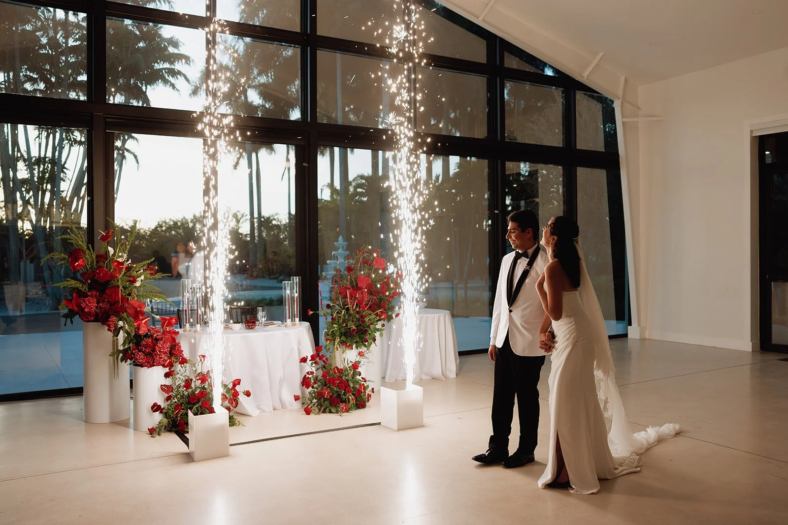 Elegant bride and groom sharing a kiss while showcasing a dramatic cascading bridal bouquet with white orchids and crimson roses at a luxury Florida wedding.